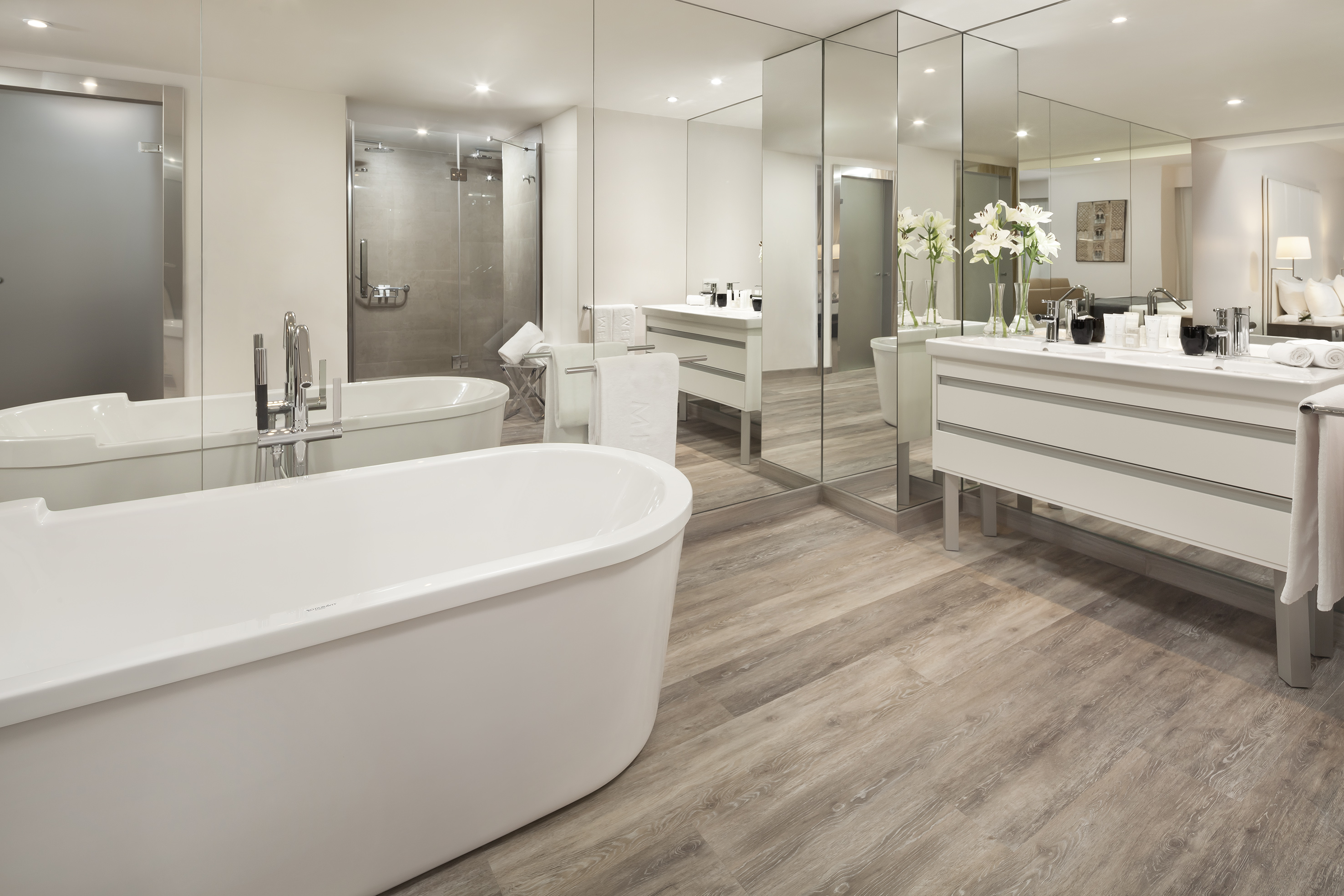 Modern bathroom with freestanding tub, double vanity, and glass shower.