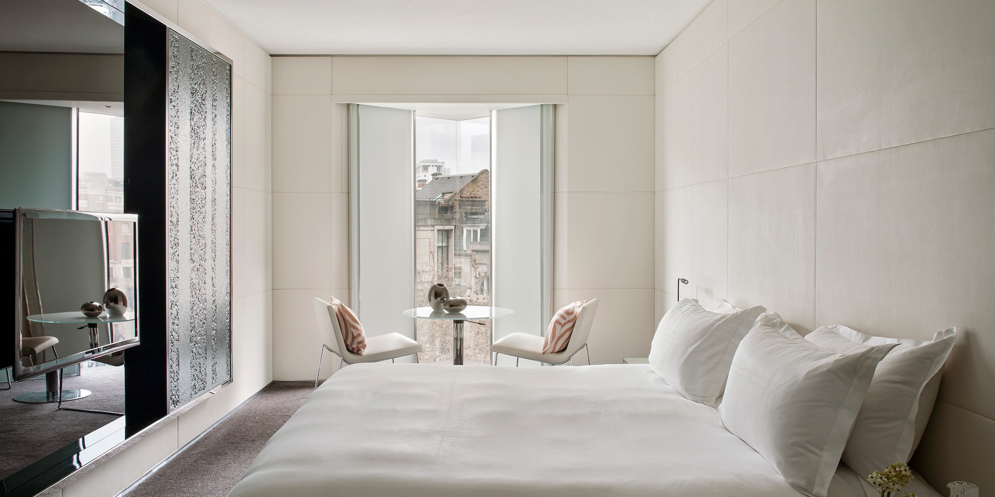 a bed with white sheets and a table and chairs in a room