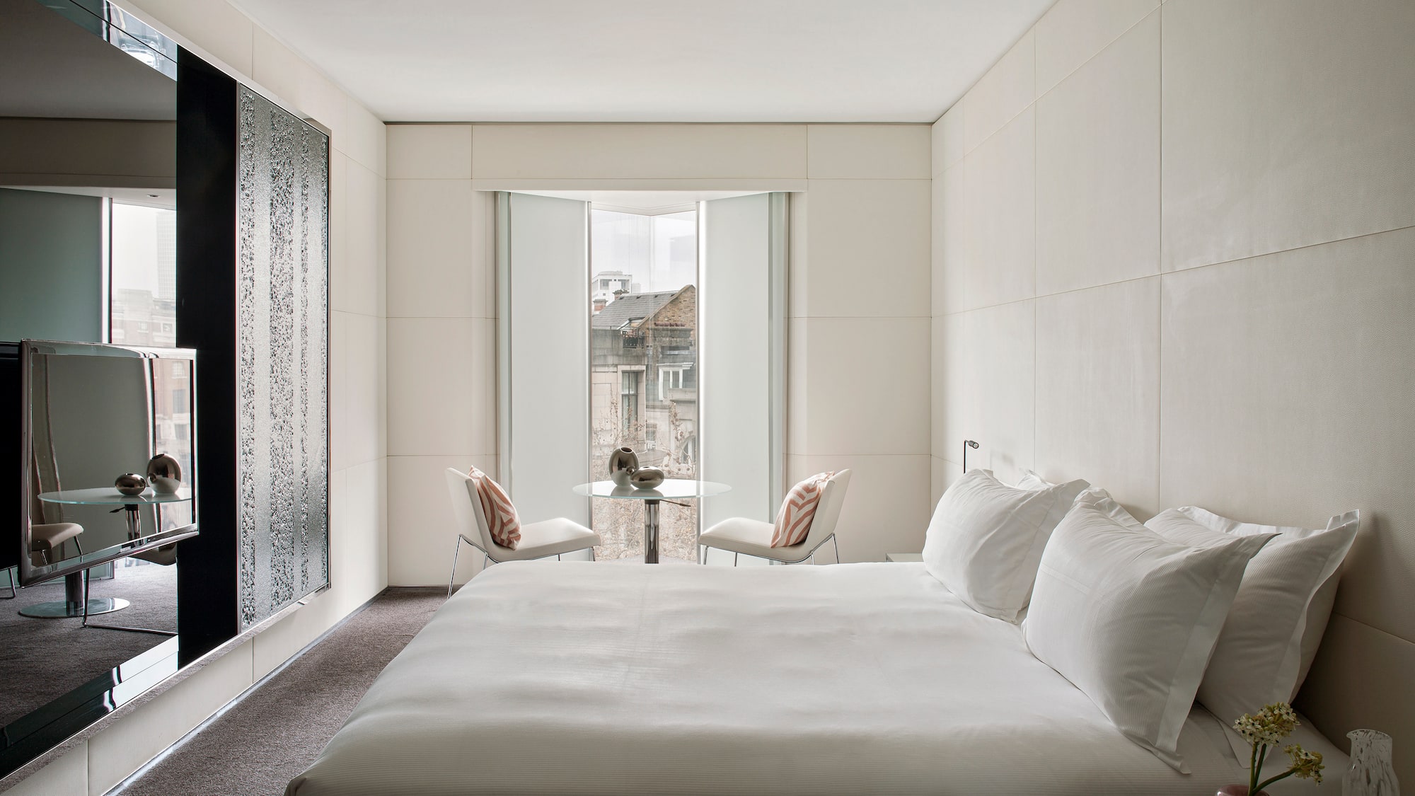 a bed with white sheets and a table and chairs in a room