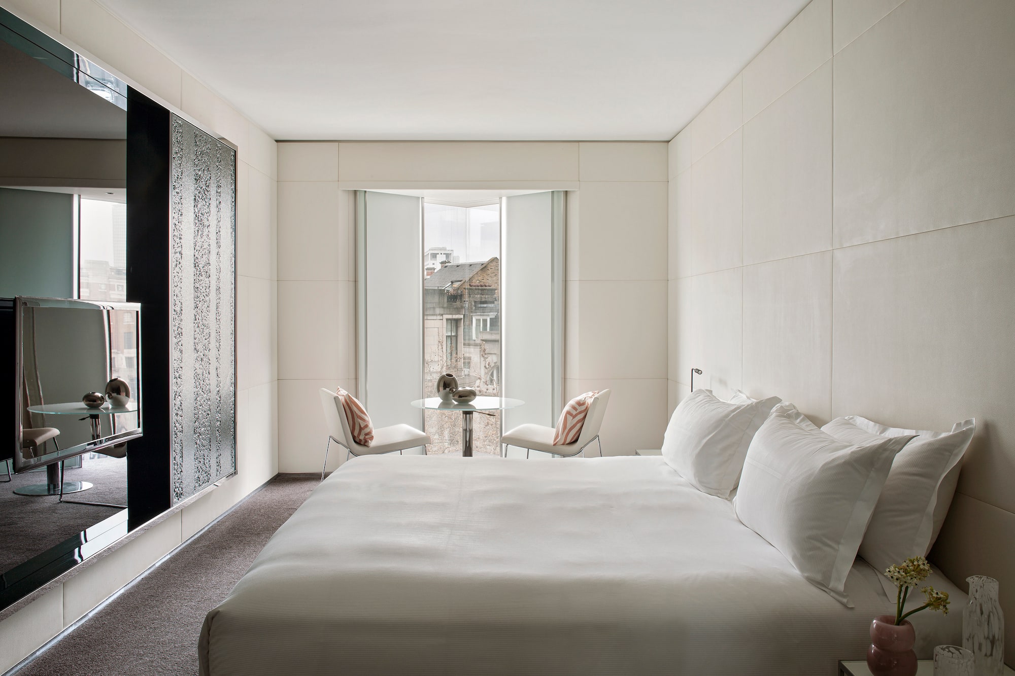 a bed with white sheets and a table and chairs in a room