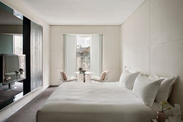 a bed with white sheets and a table and chairs in a room