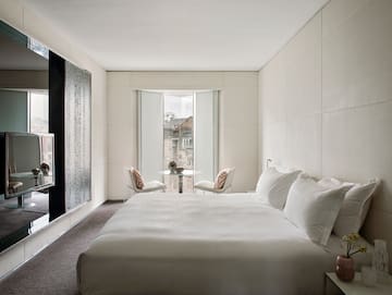 a bed with white sheets and a table and chairs in a room