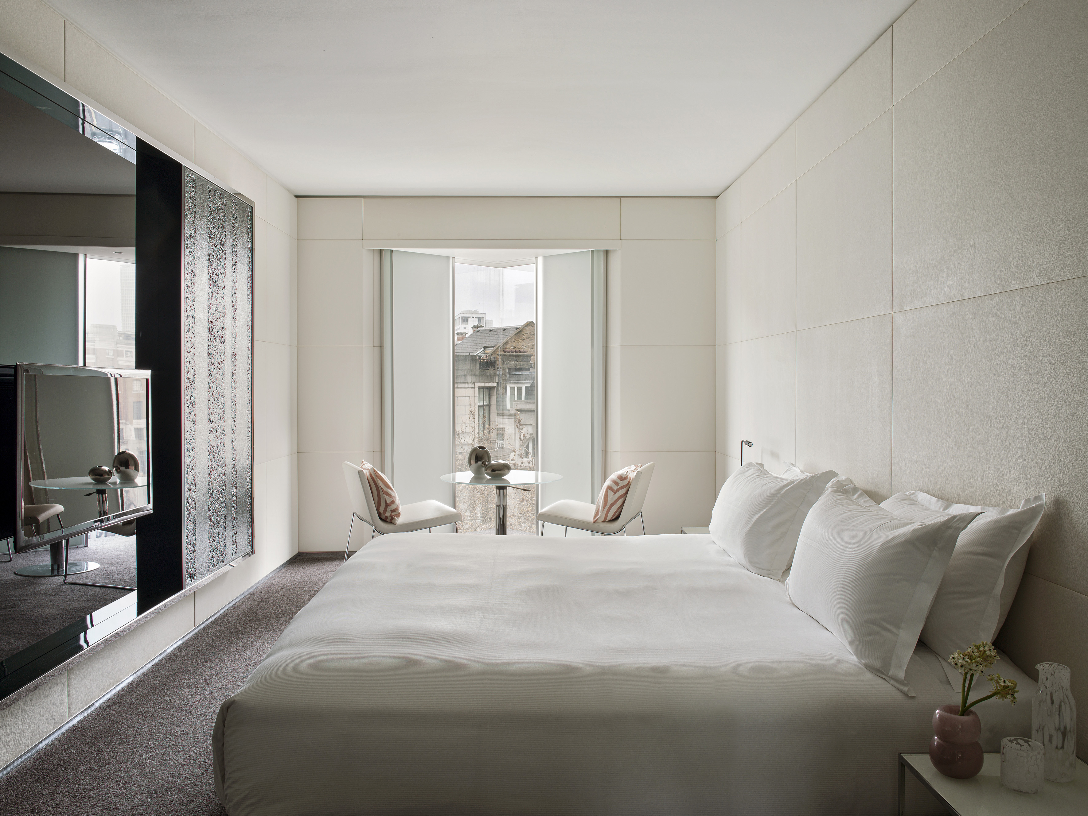a bed with white sheets and a table and chairs in a room