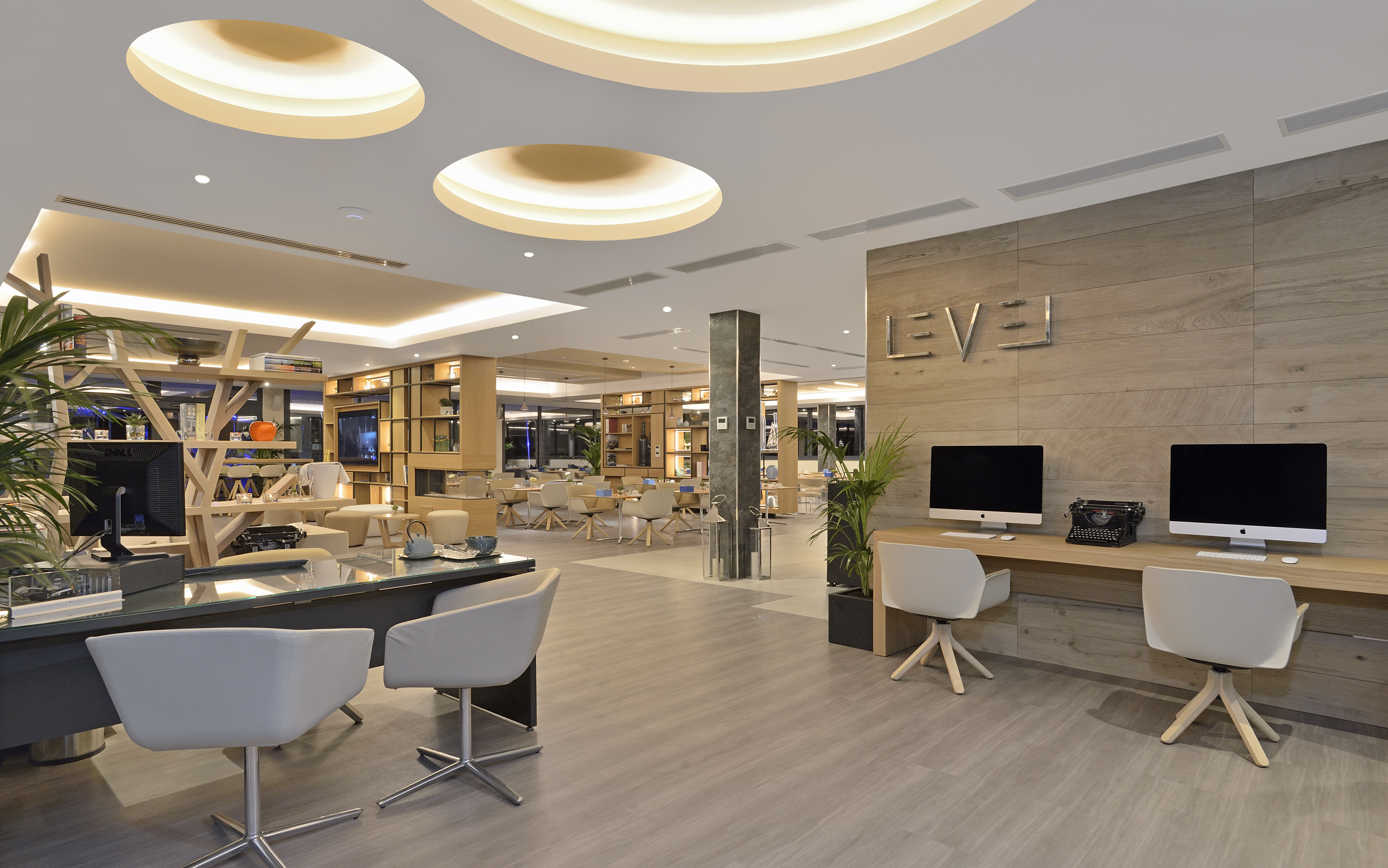 Modern hotel lobby with computers, sleek desks, and lounge seating.