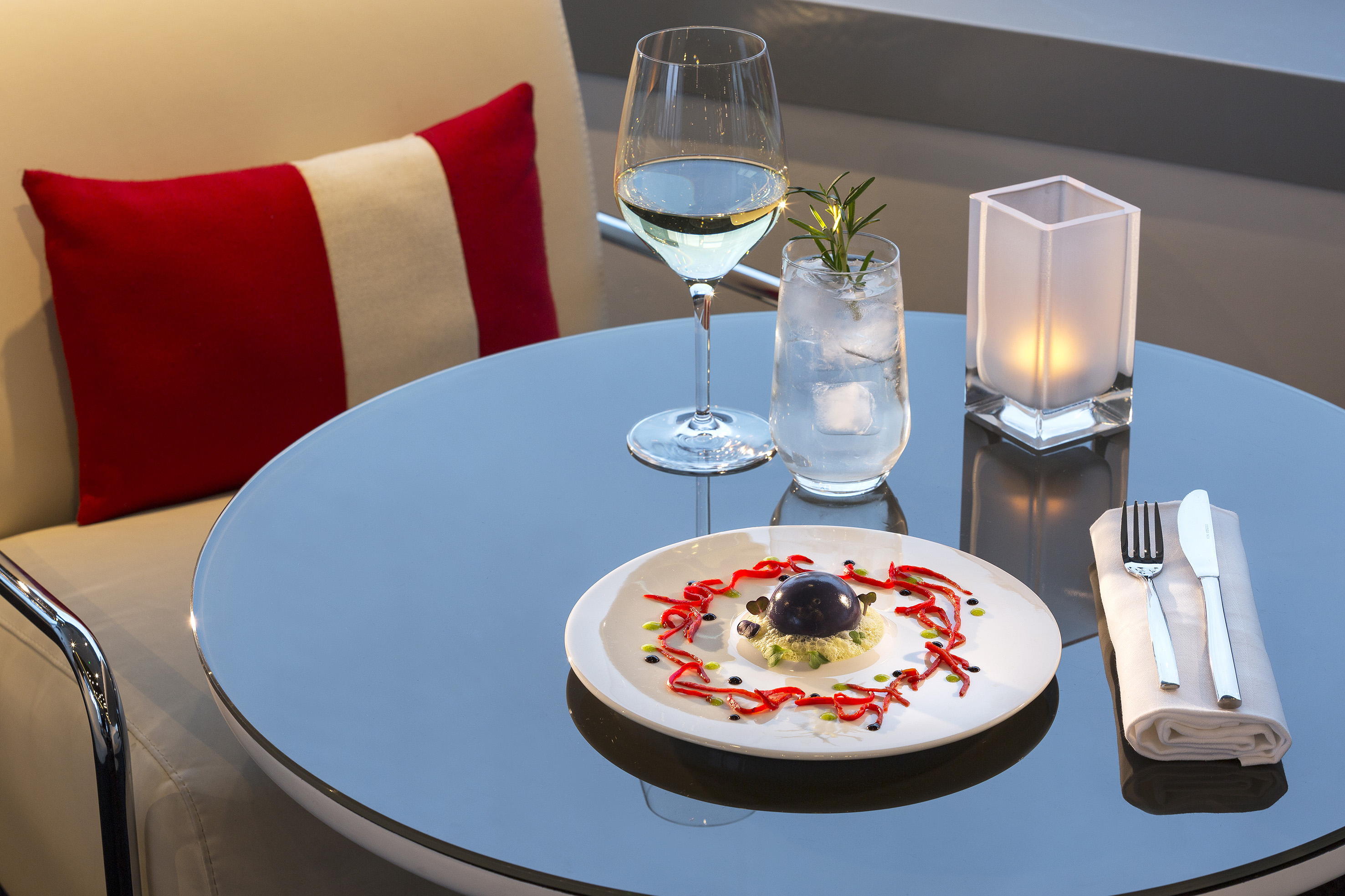 Fine dining dessert, white wine, and cocktail on modern outdoor table with candle.