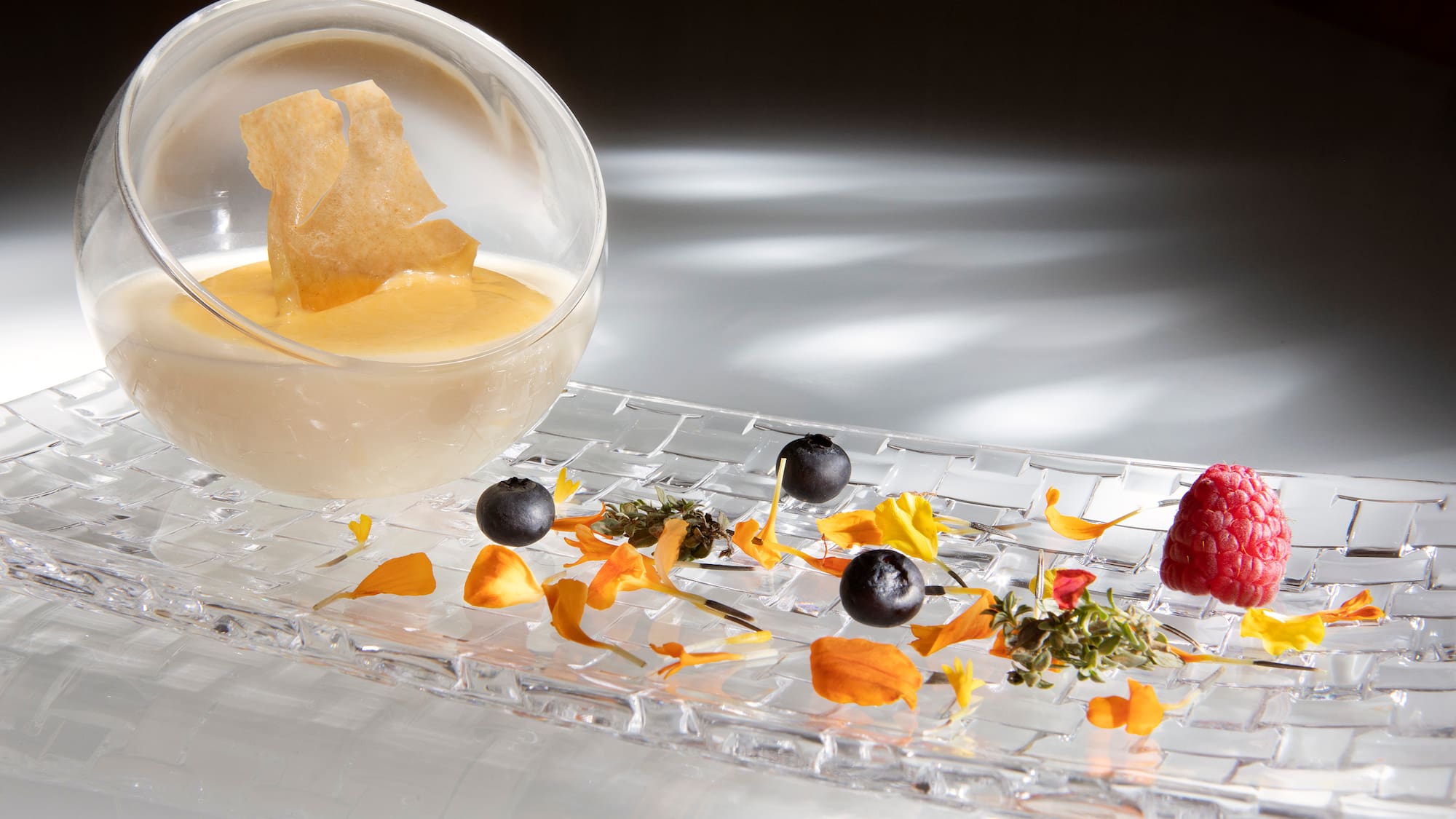a glass bowl with a bowl of liquid and fruit on a glass plate