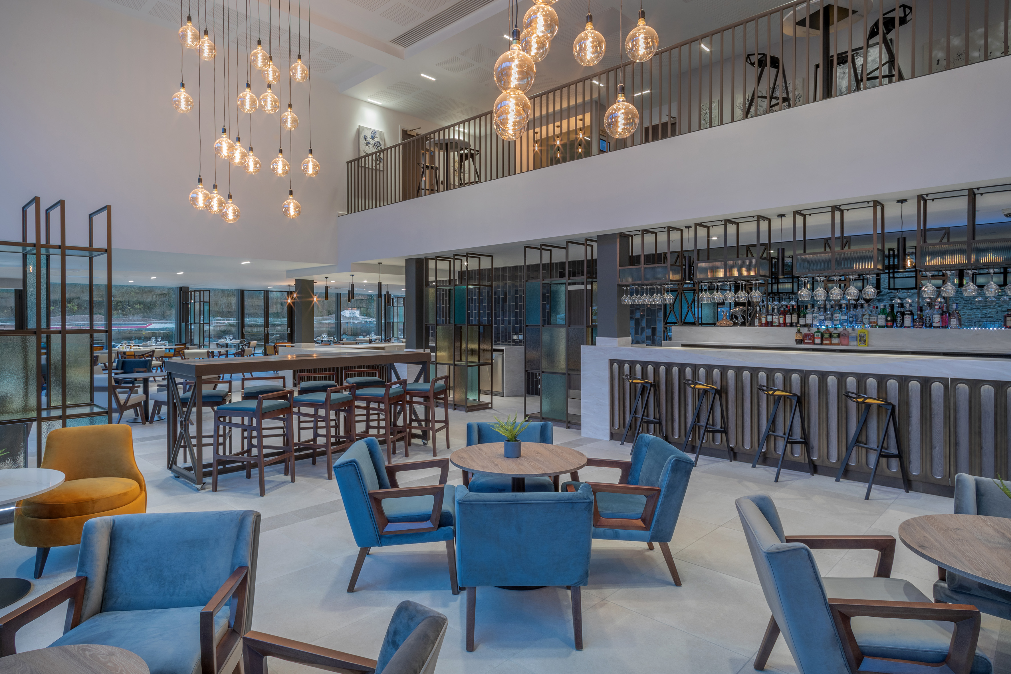 Stylish modern hotel lounge bar with varied seating, lighting, mezzanine.