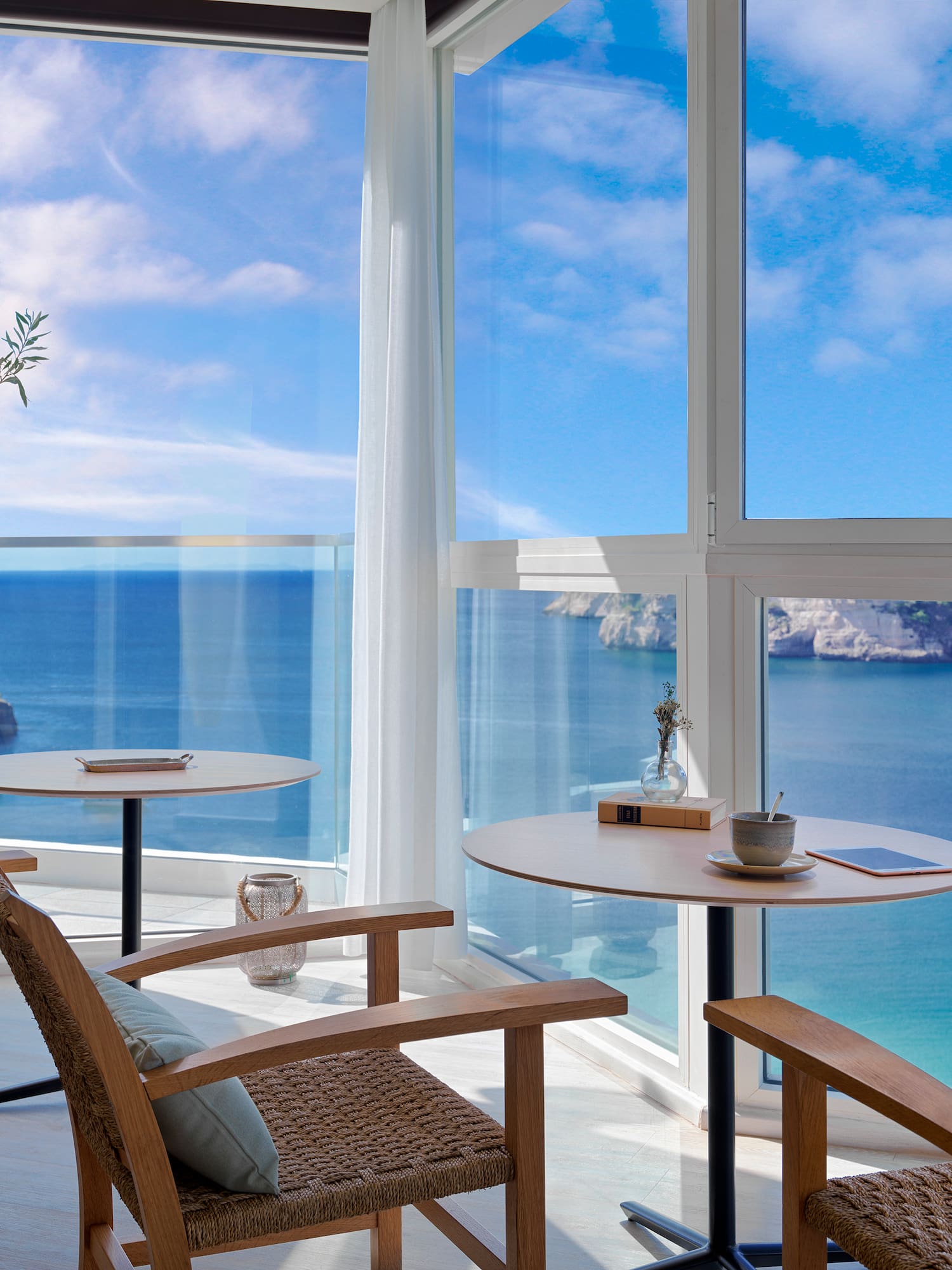 a room with a view of the ocean and a table and chairs