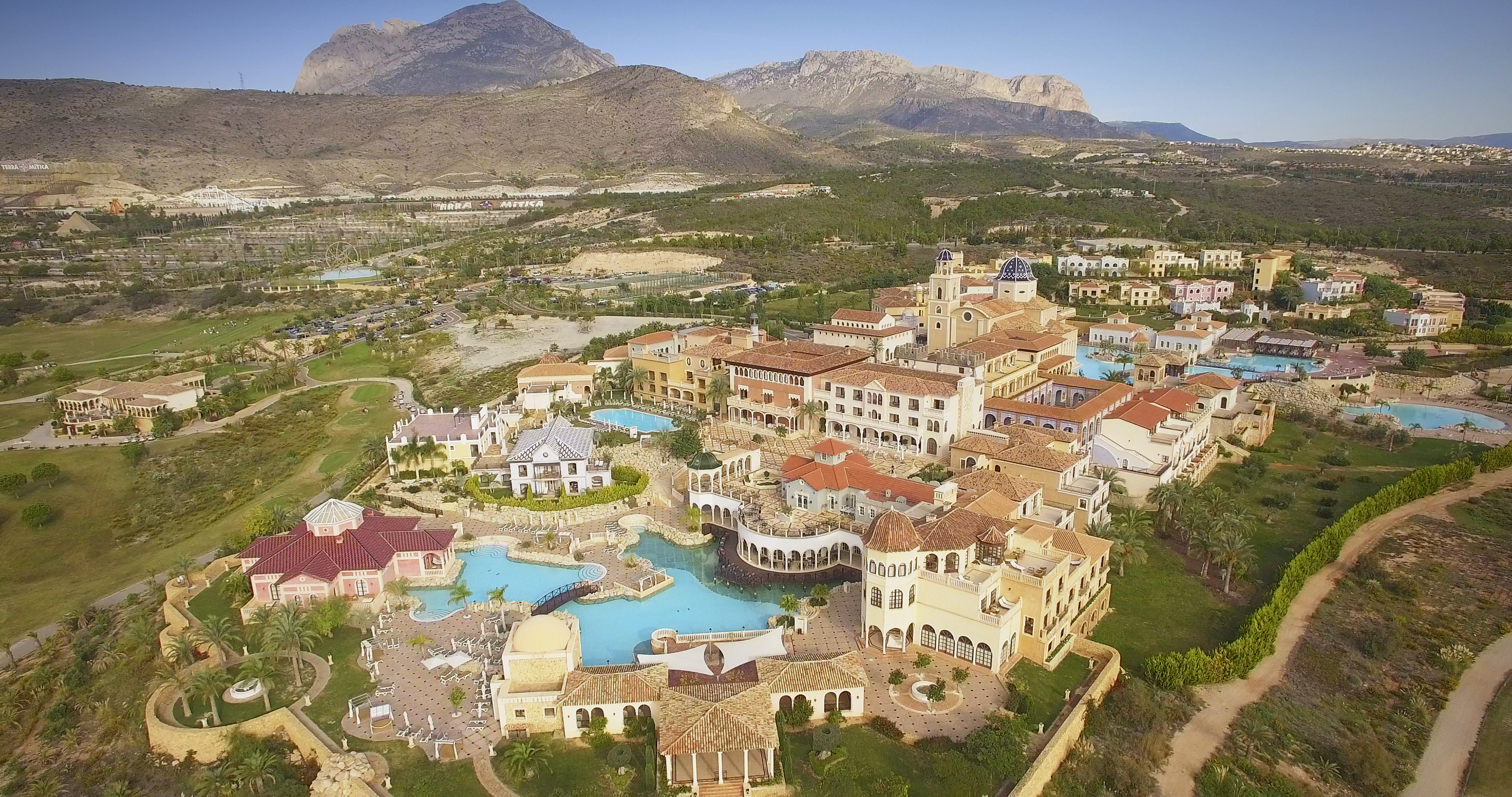 a large building with a pool and a large building with a large mountain in the background