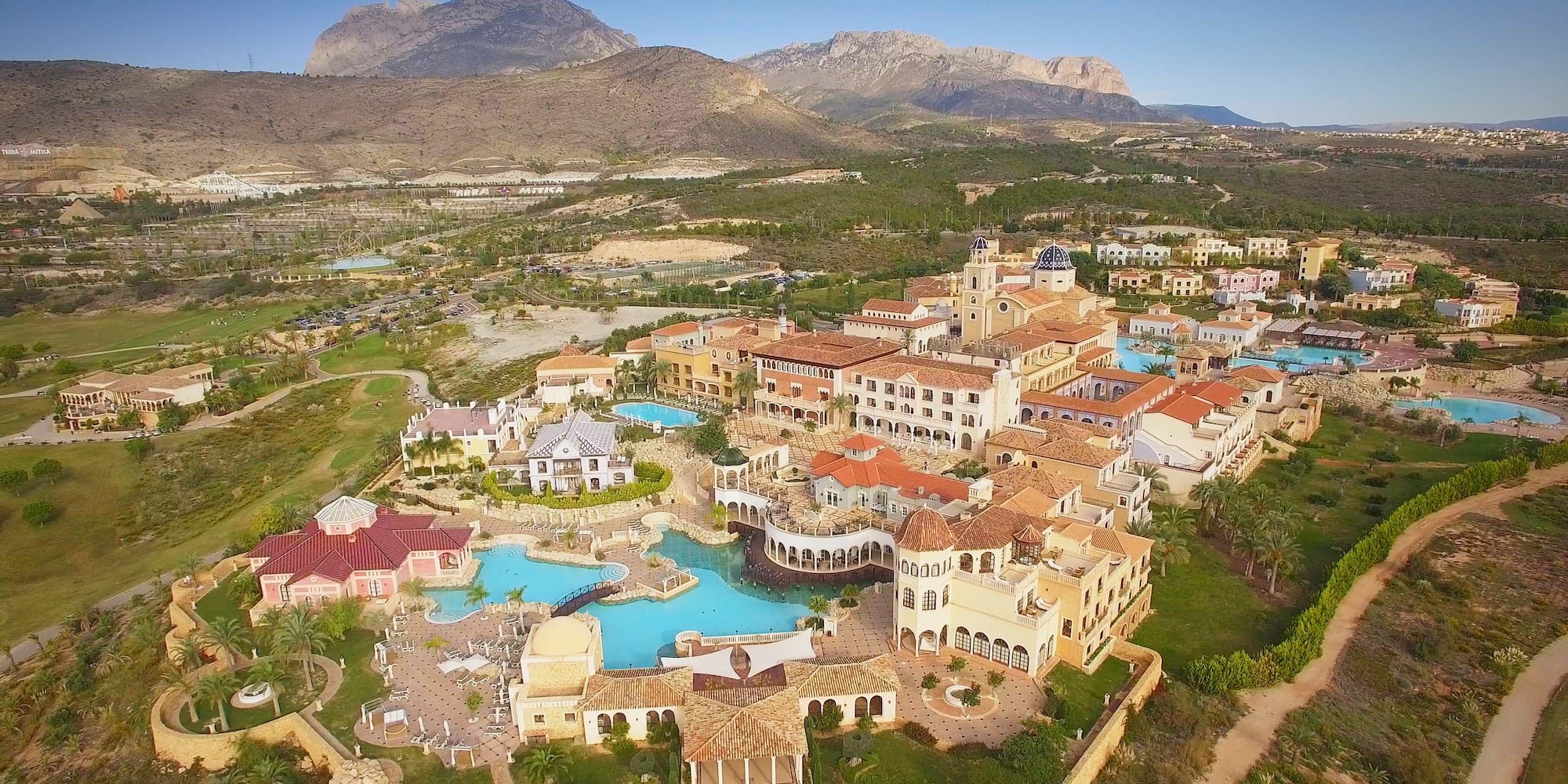a large building with a pool and a large building with a large mountain in the background