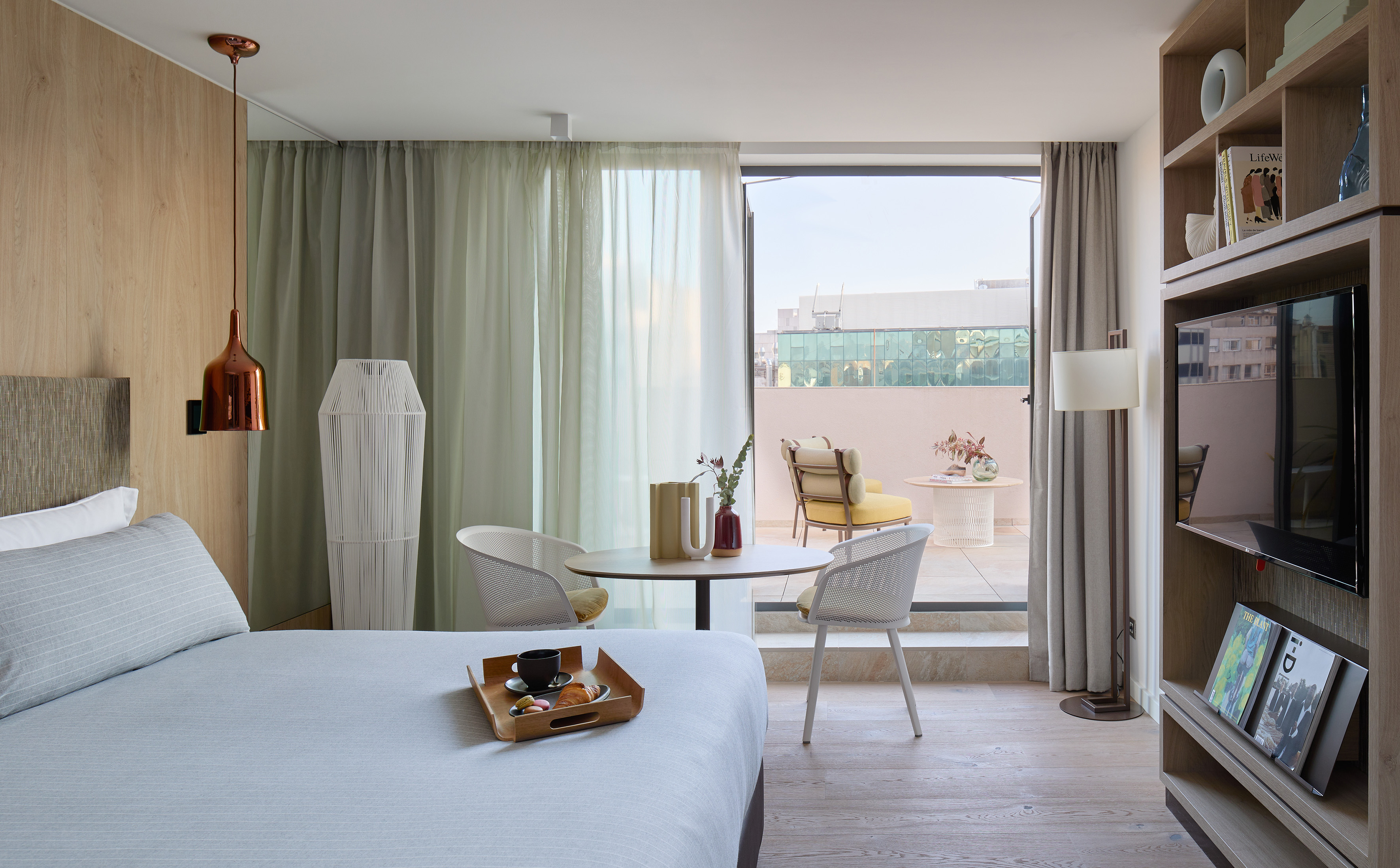 Contemporary hotel suite with bed, dining table, and private balcony.