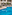 Hotel outdoor swimming pool, sun loungers, palm trees, and modern building.