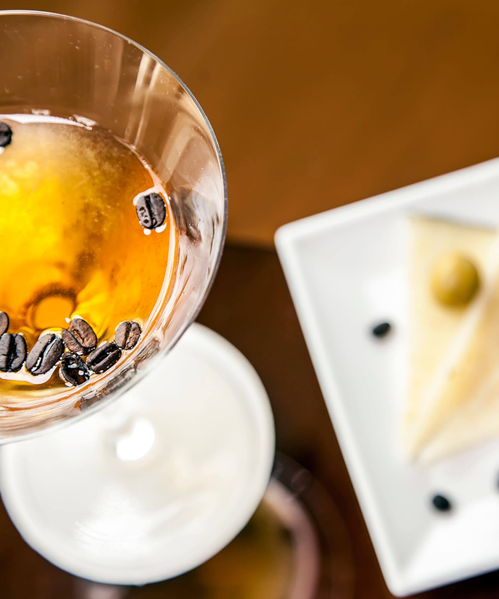 a glass with brown liquid and coffee beans in it