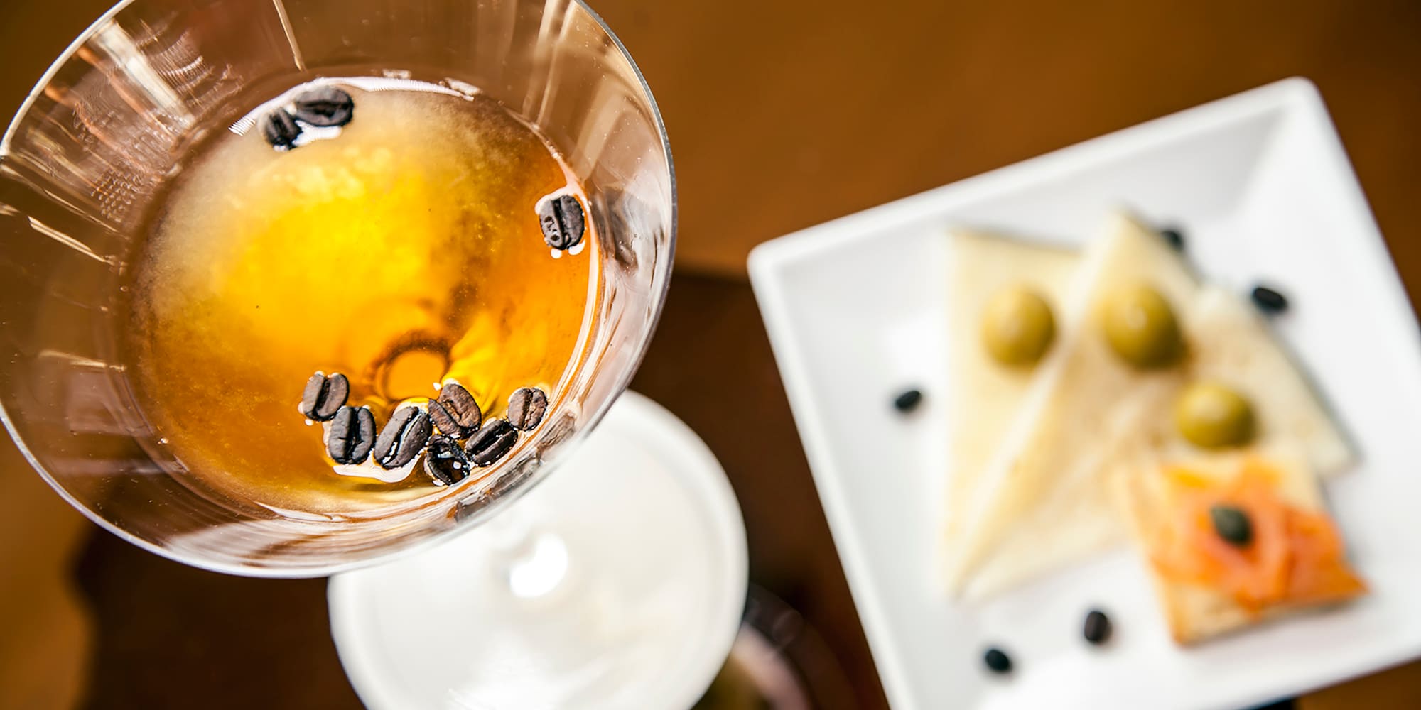 a glass with brown liquid and coffee beans in it