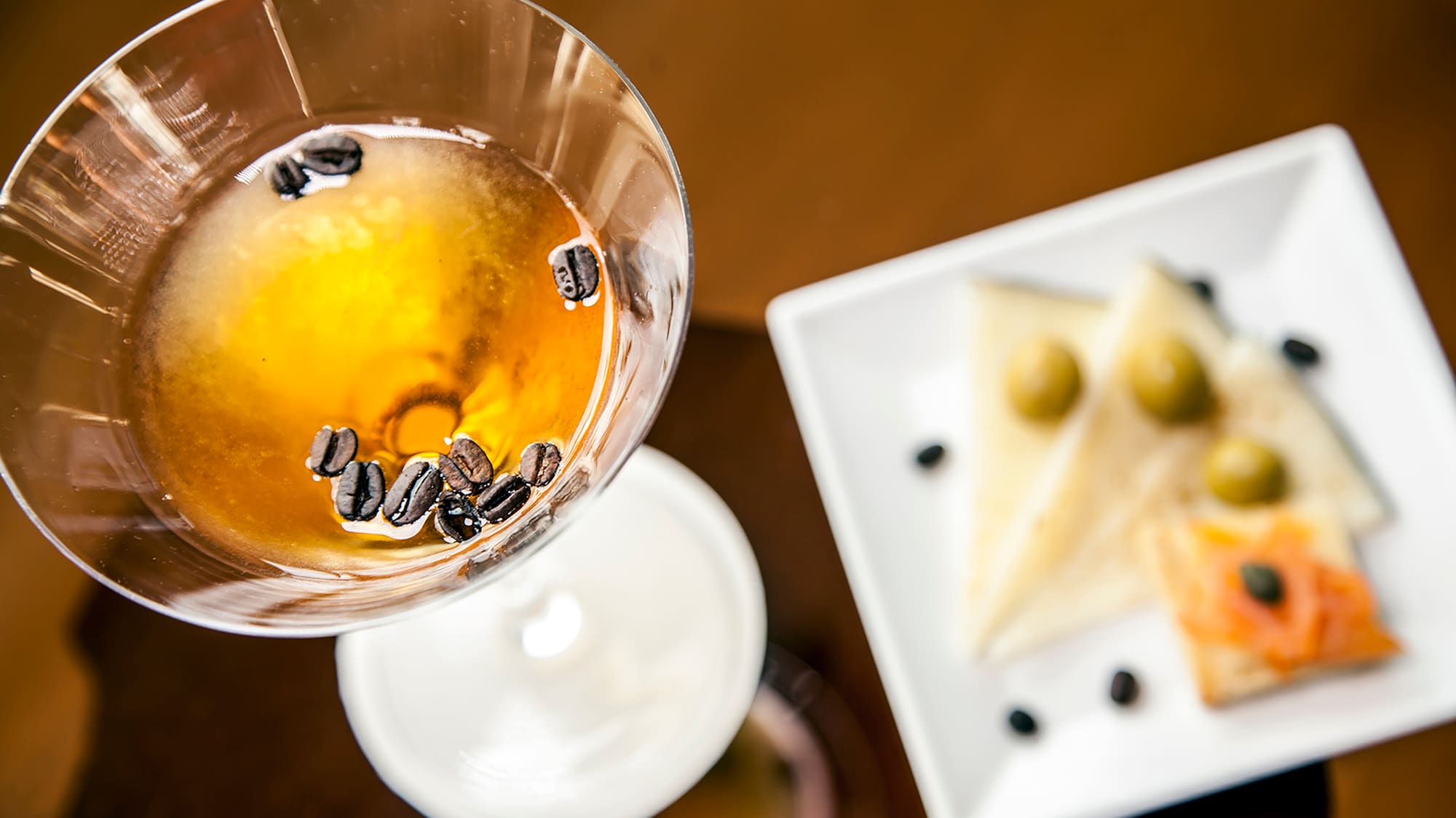 a glass with brown liquid and coffee beans in it