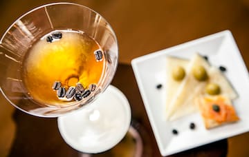 a glass with brown liquid and coffee beans in it