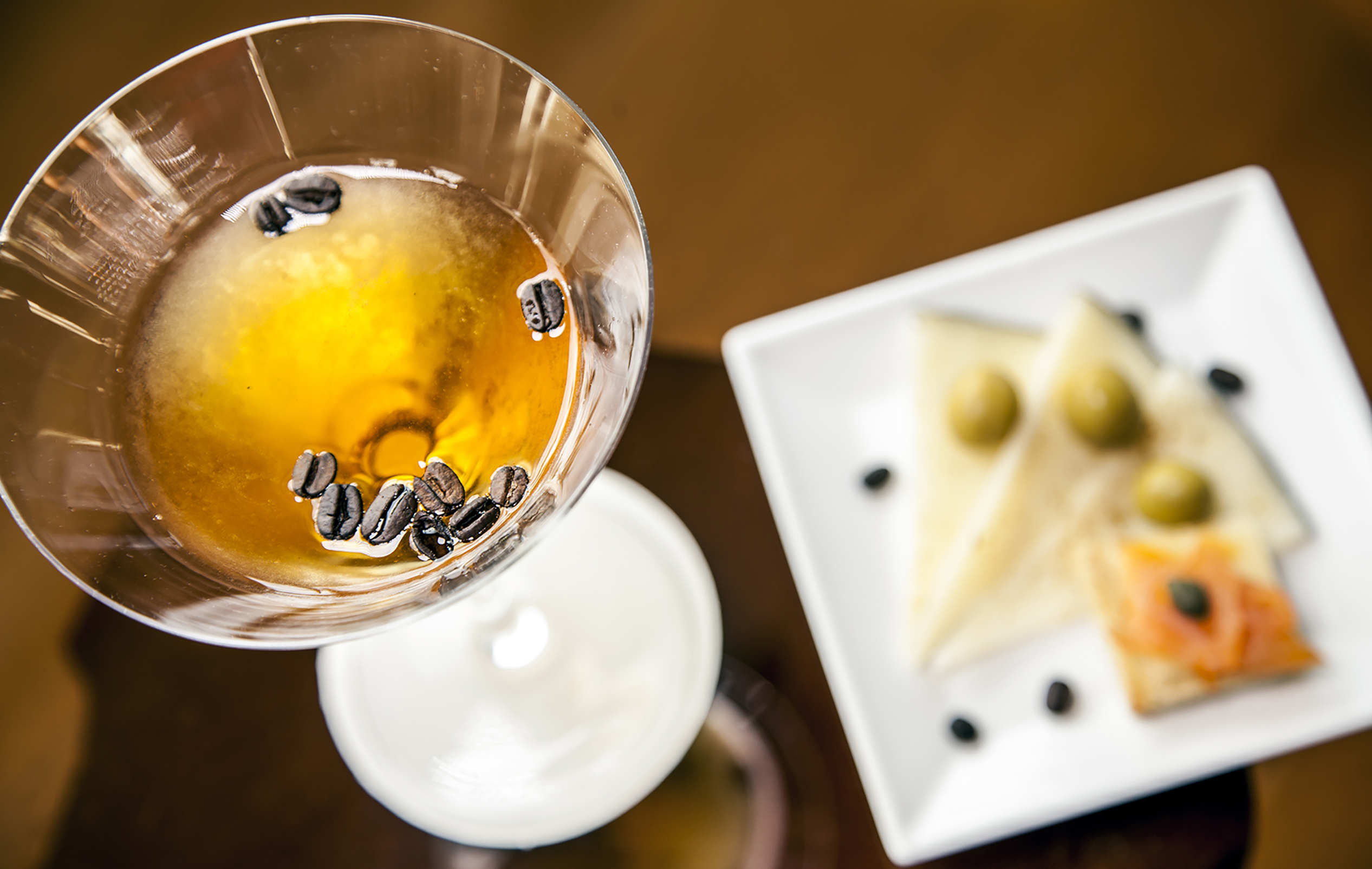 a glass with brown liquid and coffee beans in it