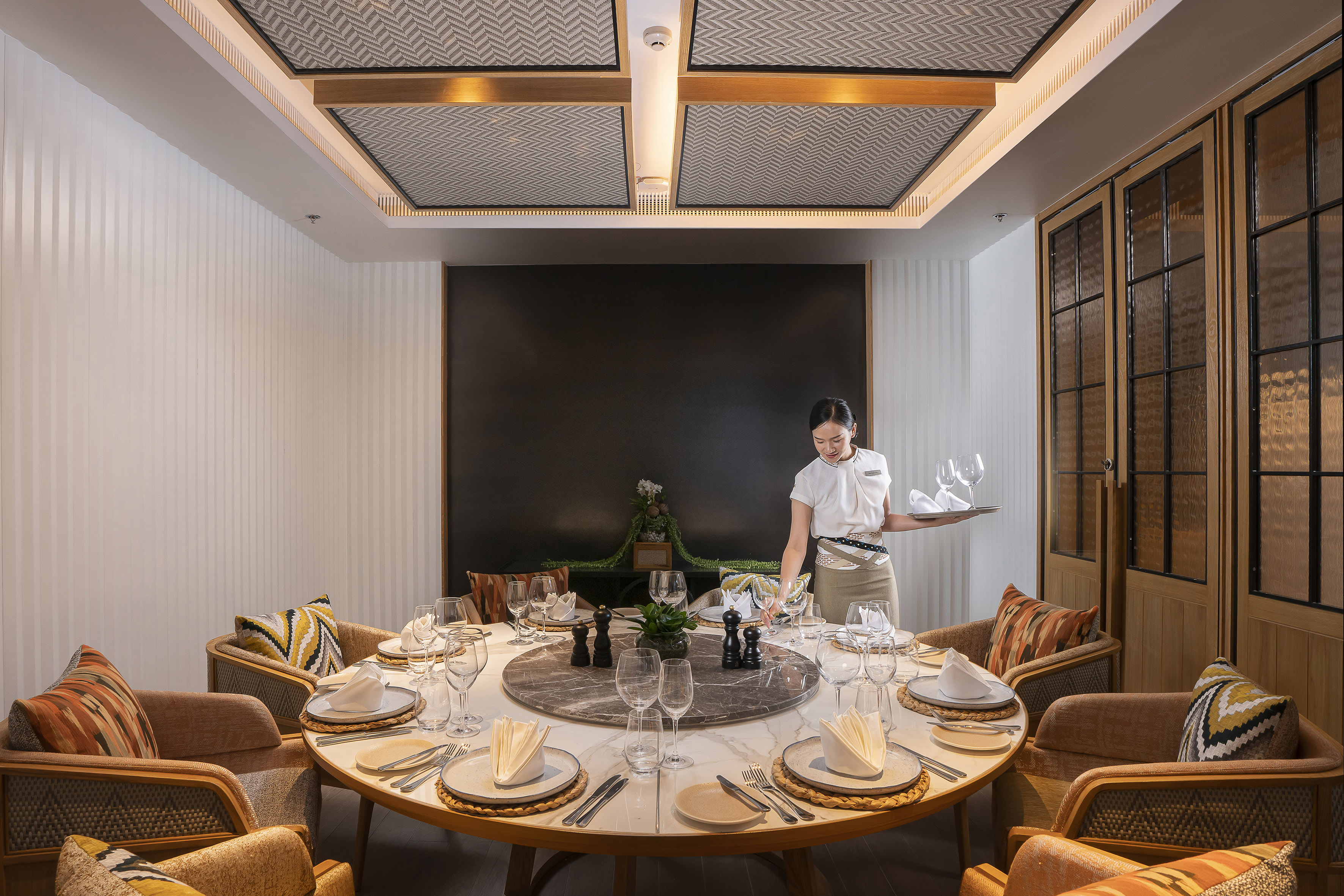 Private dining room with server arranging an elegantly set round table.