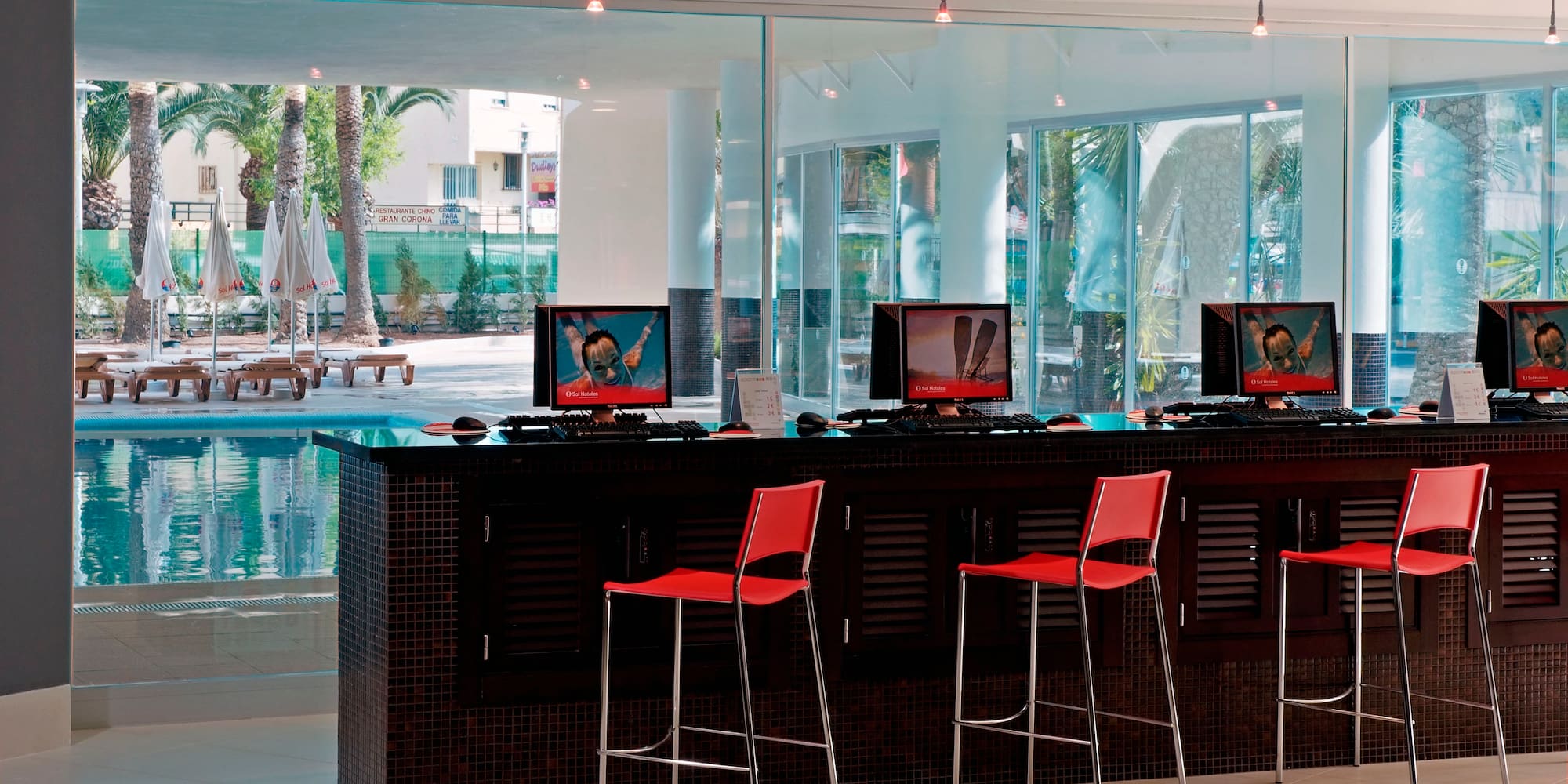 a room with a bar with computers and chairs