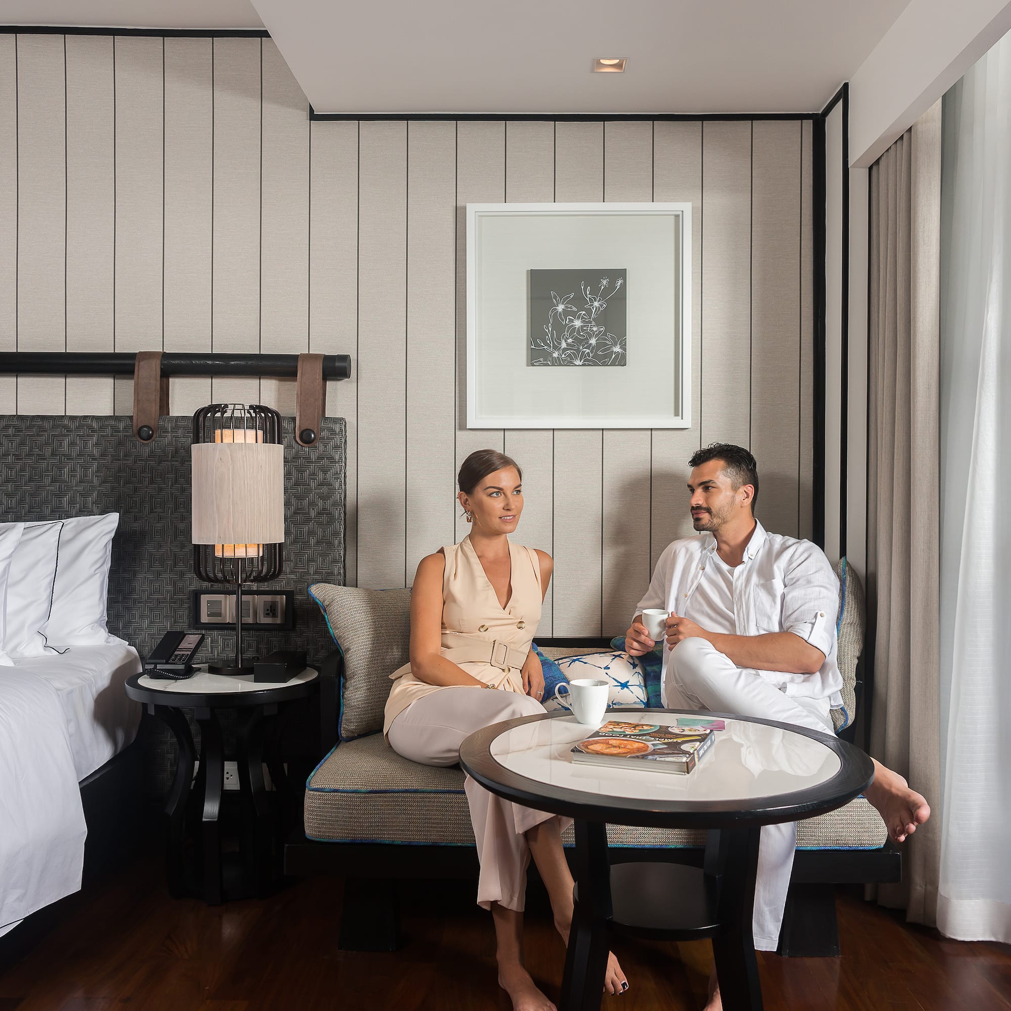a man and woman sitting on a couch in a hotel room