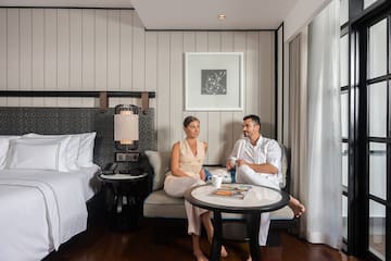 a man and woman sitting on a couch in a hotel room