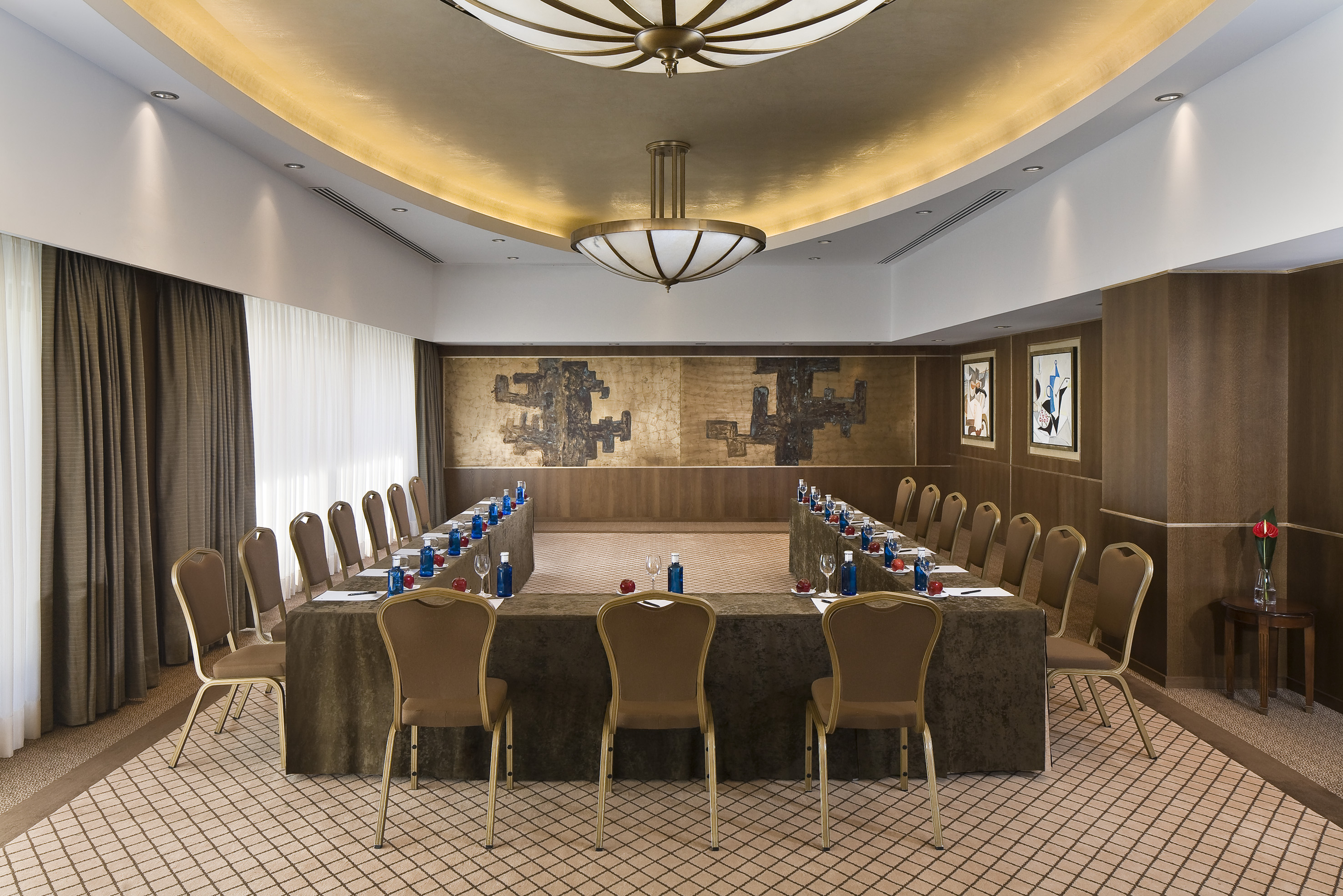 U-shaped conference room with brown chairs, set tables, and abstract wall art.