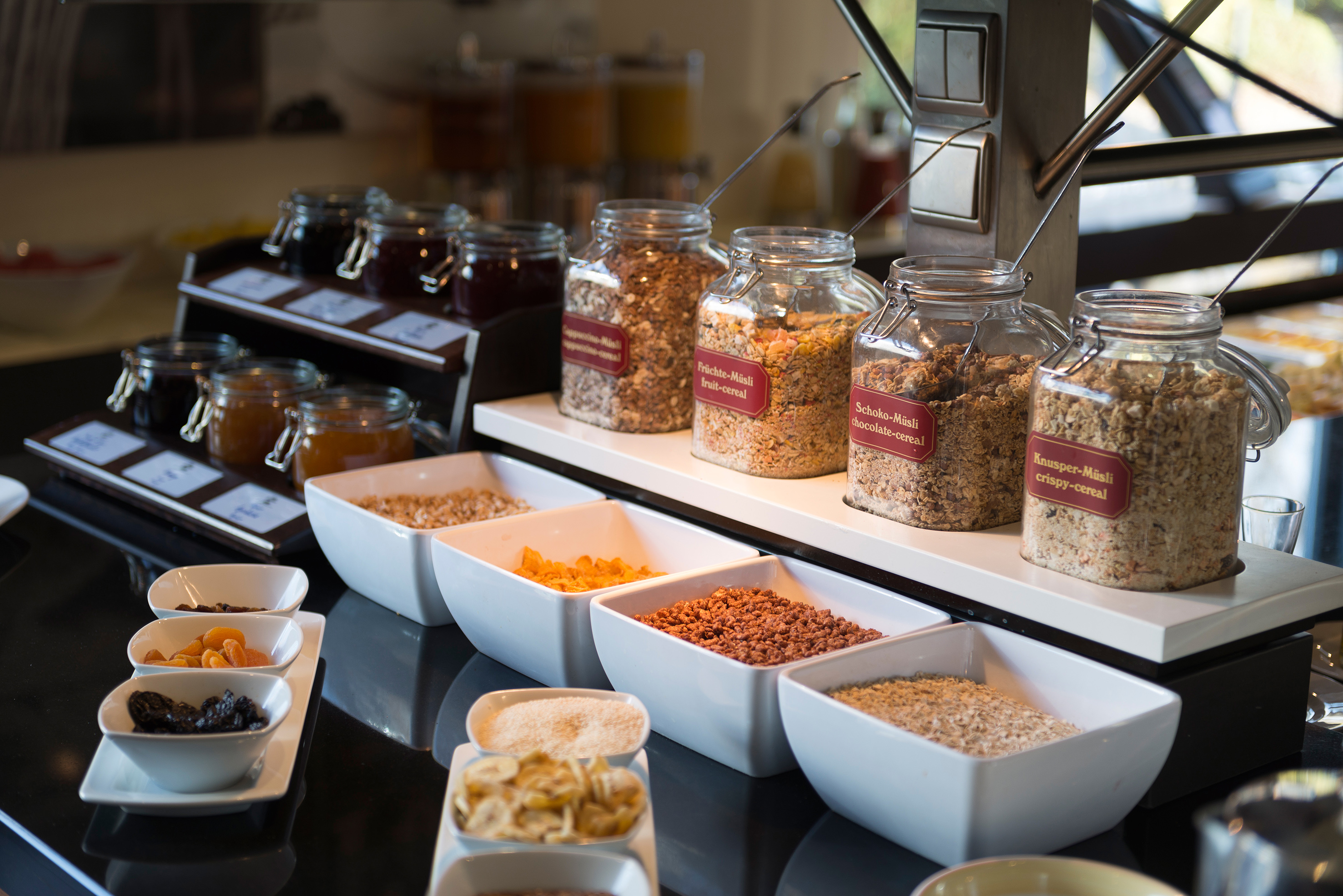 Hotel breakfast buffet: muesli, cereals, dried fruits, and jams.