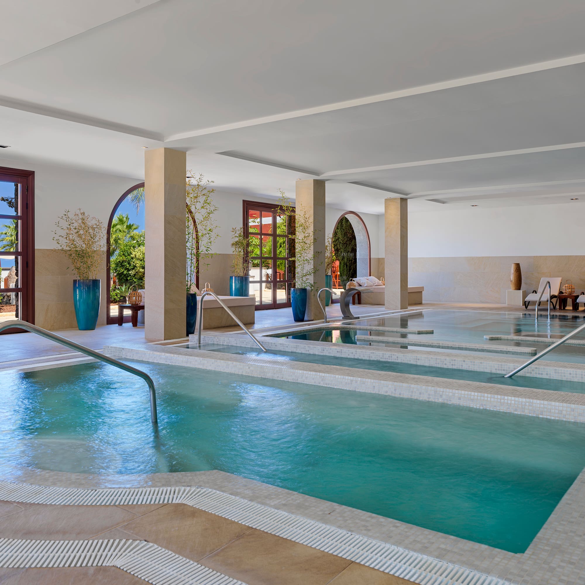 Luxury indoor spa with tiered hydrotherapy pools and natural light.