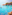 Boats on clear turquoise Mediterranean bay, rocky coast, green trees.
