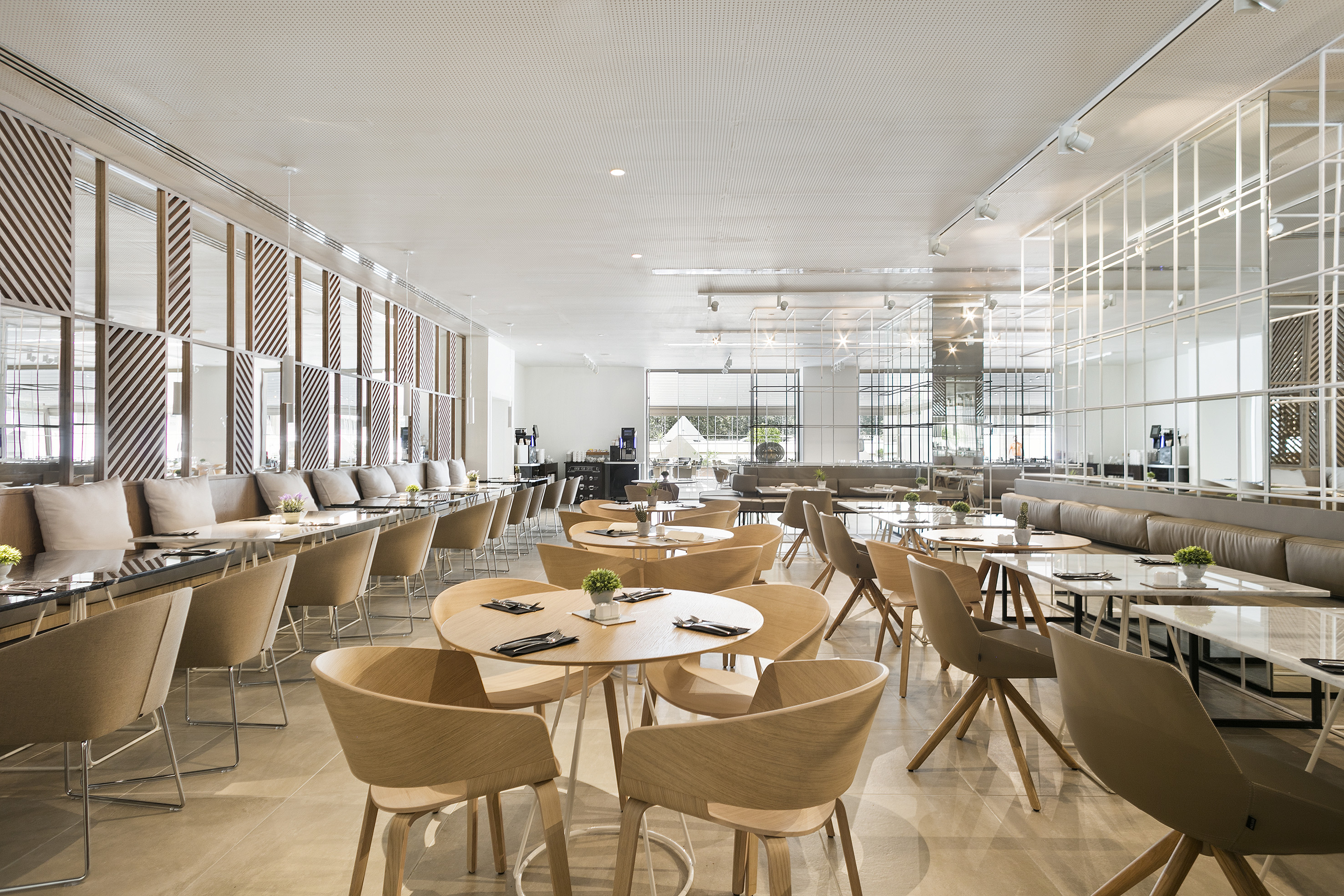 Modern restaurant interior: sleek wood chairs, marble tables, booth seating.