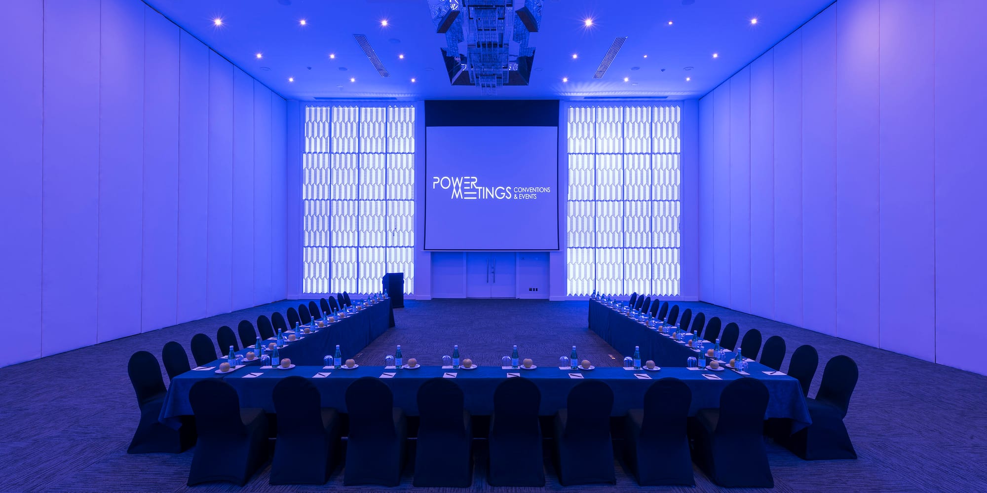 a room with a large screen and a table with chairs