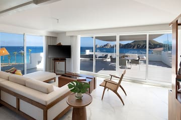 a living room with a television and a view of the ocean