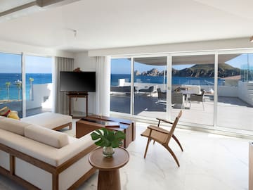 a living room with a television and a view of the ocean