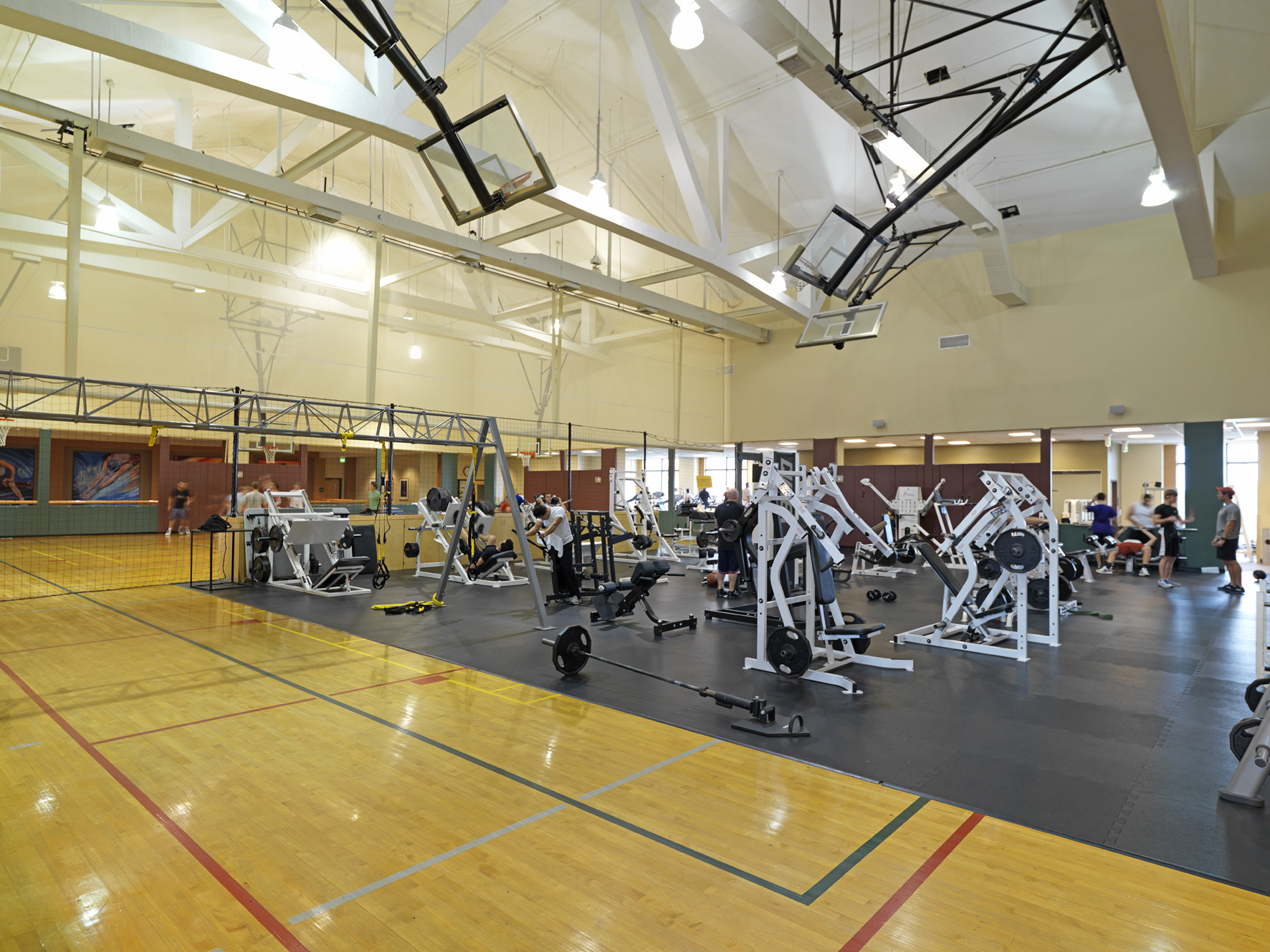 Gym with weight machines, people exercising, and a wooden basketball court. - ESPN Wide World Complex - Meliá Orlando Celebration, Orlando