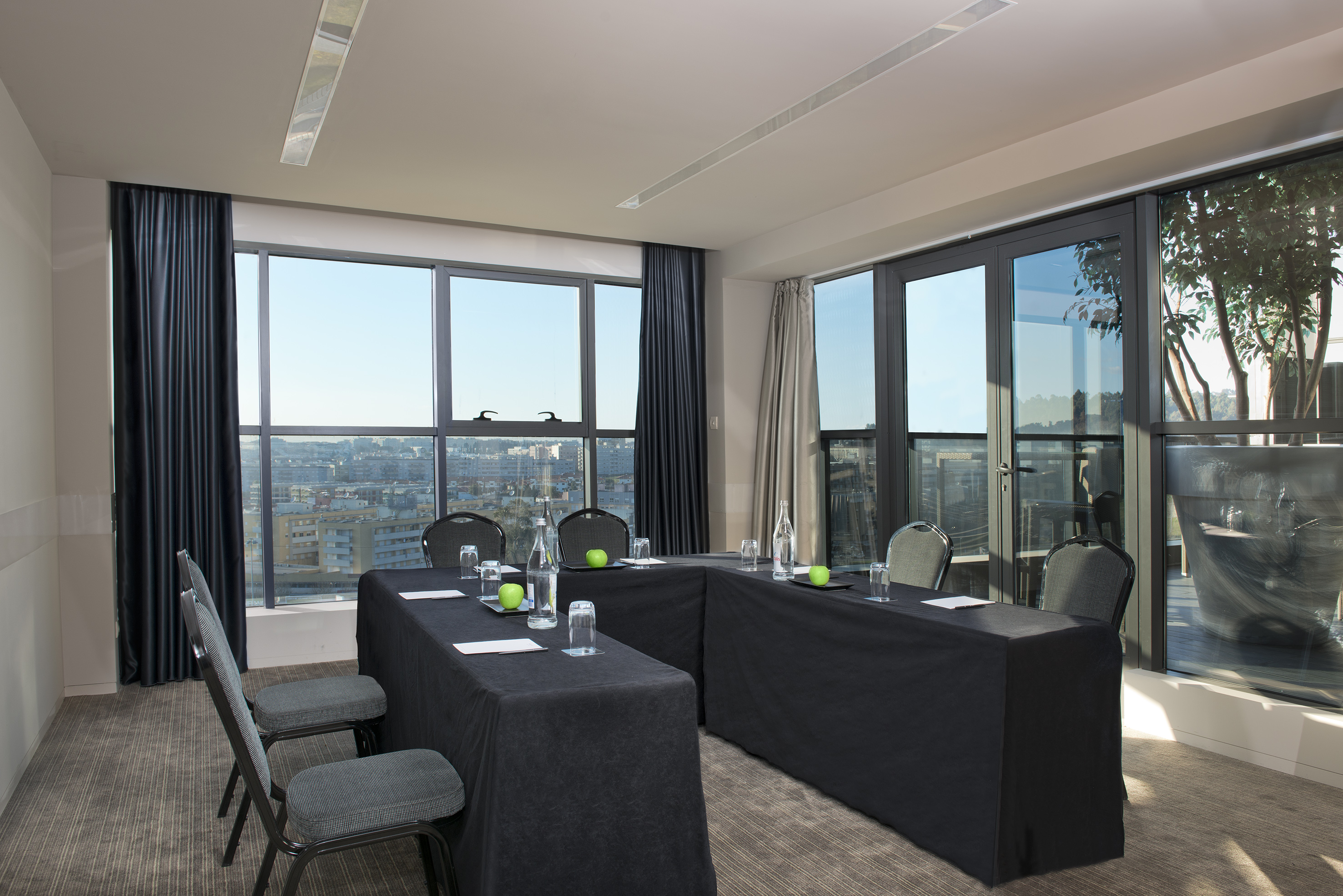 Modern conference room with U-shaped table, city view, and natural light.