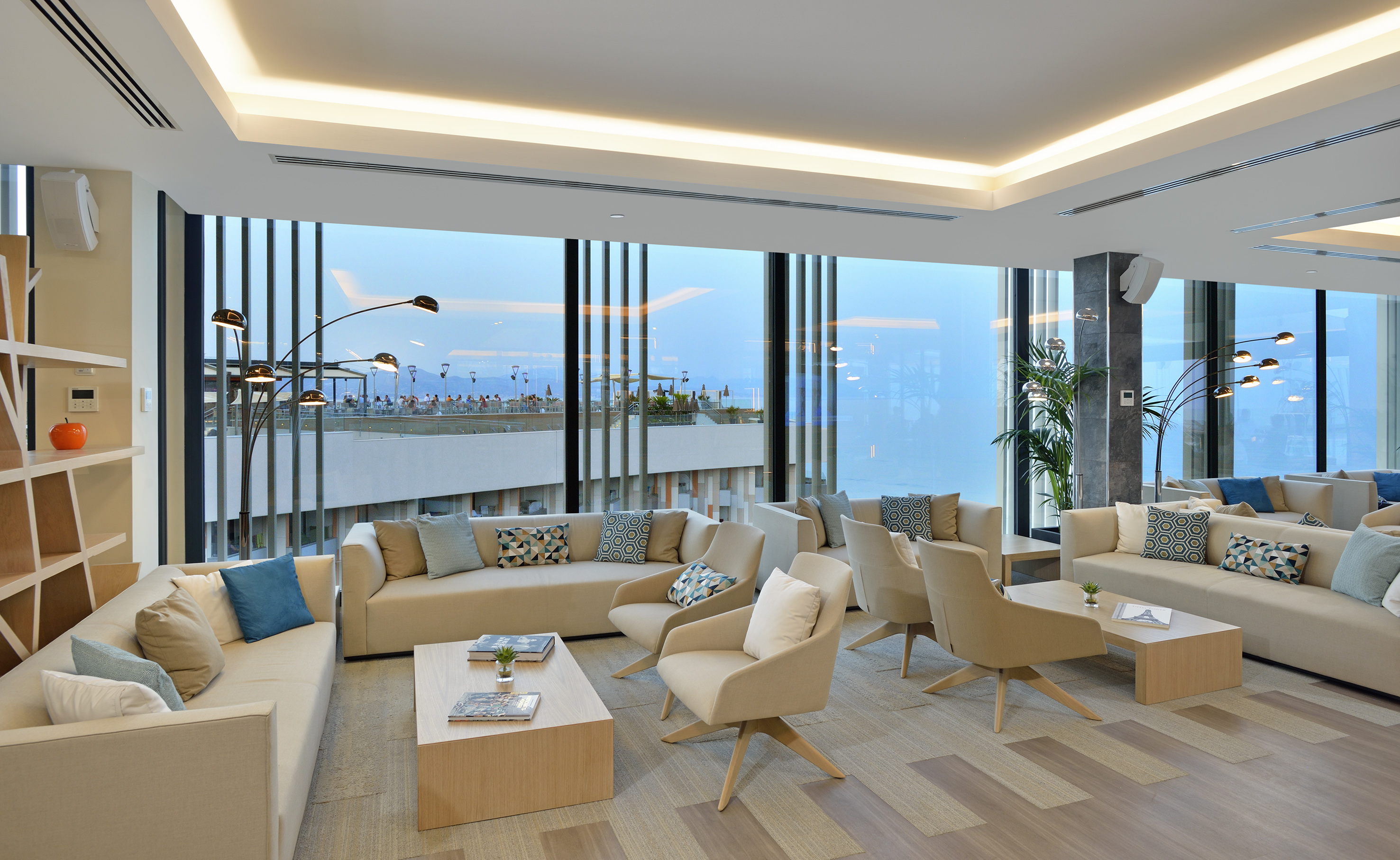 Modern lounge interior with comfortable beige seating and large panoramic windows.