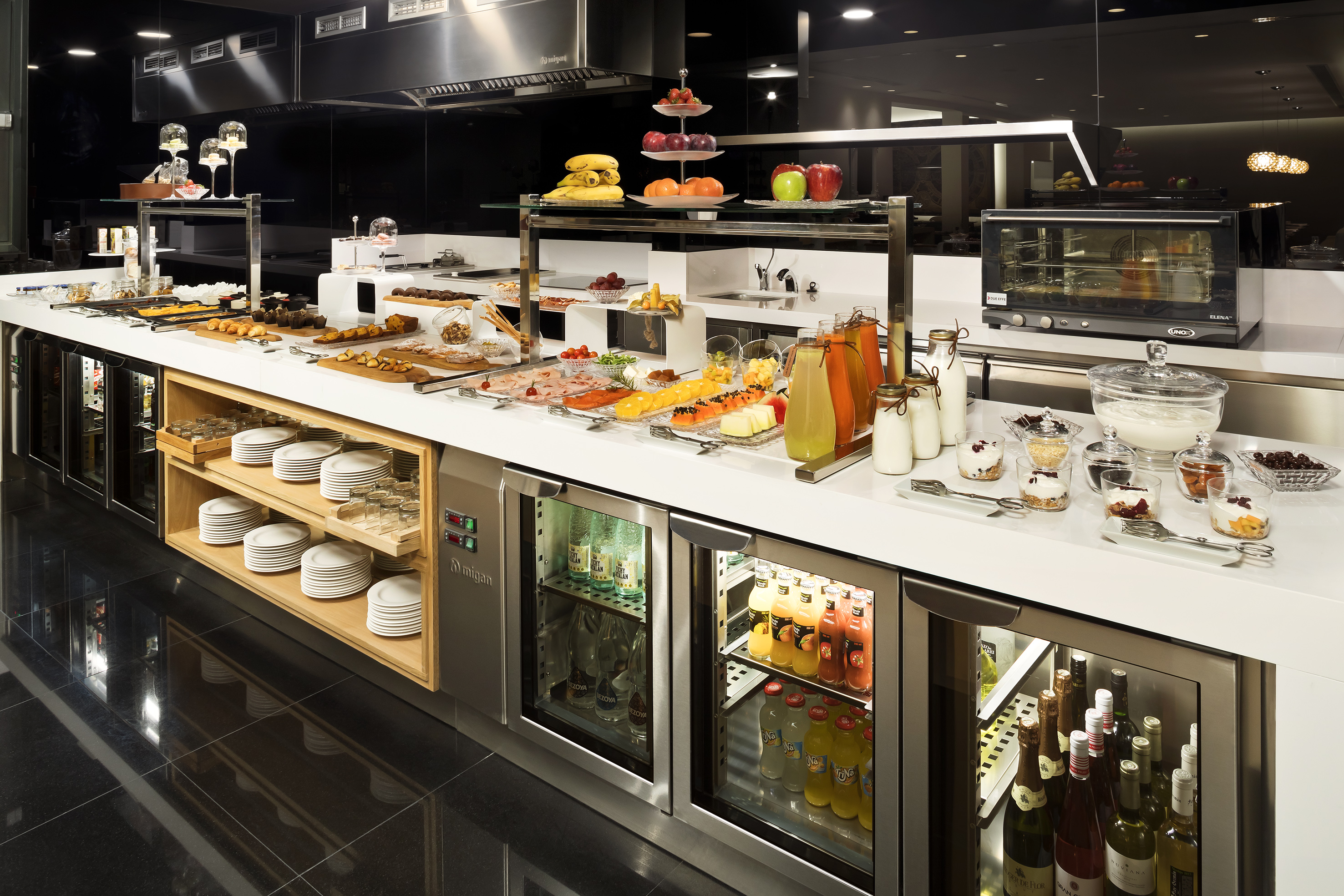 Hotel breakfast buffet with fresh fruits, pastries, juices, and cold cuts.