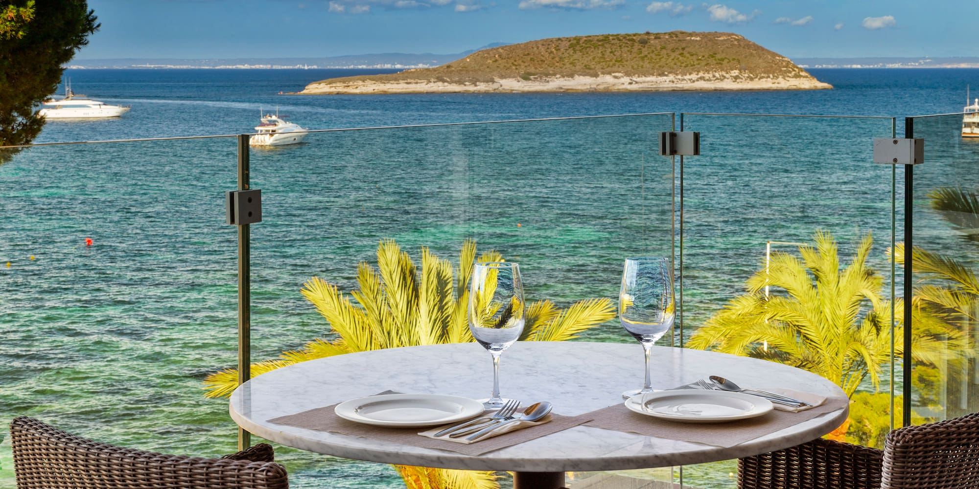 a table with plates and glasses on it overlooking a body of water