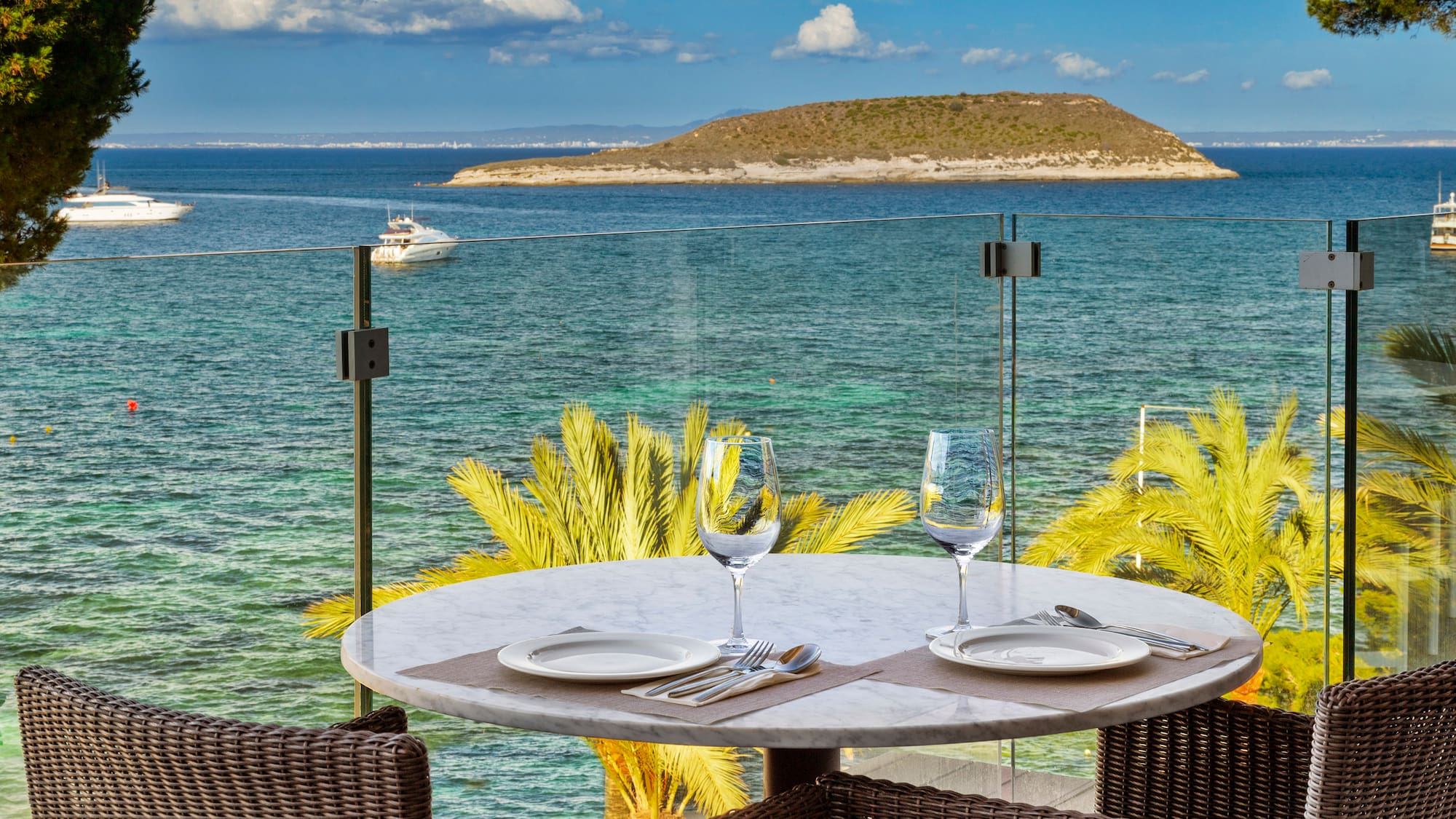 a table with plates and glasses on it overlooking a body of water