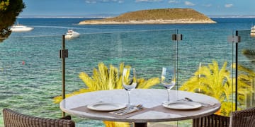 a table with plates and glasses on it overlooking a body of water