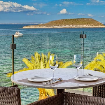 a table with plates and glasses on it overlooking a body of water