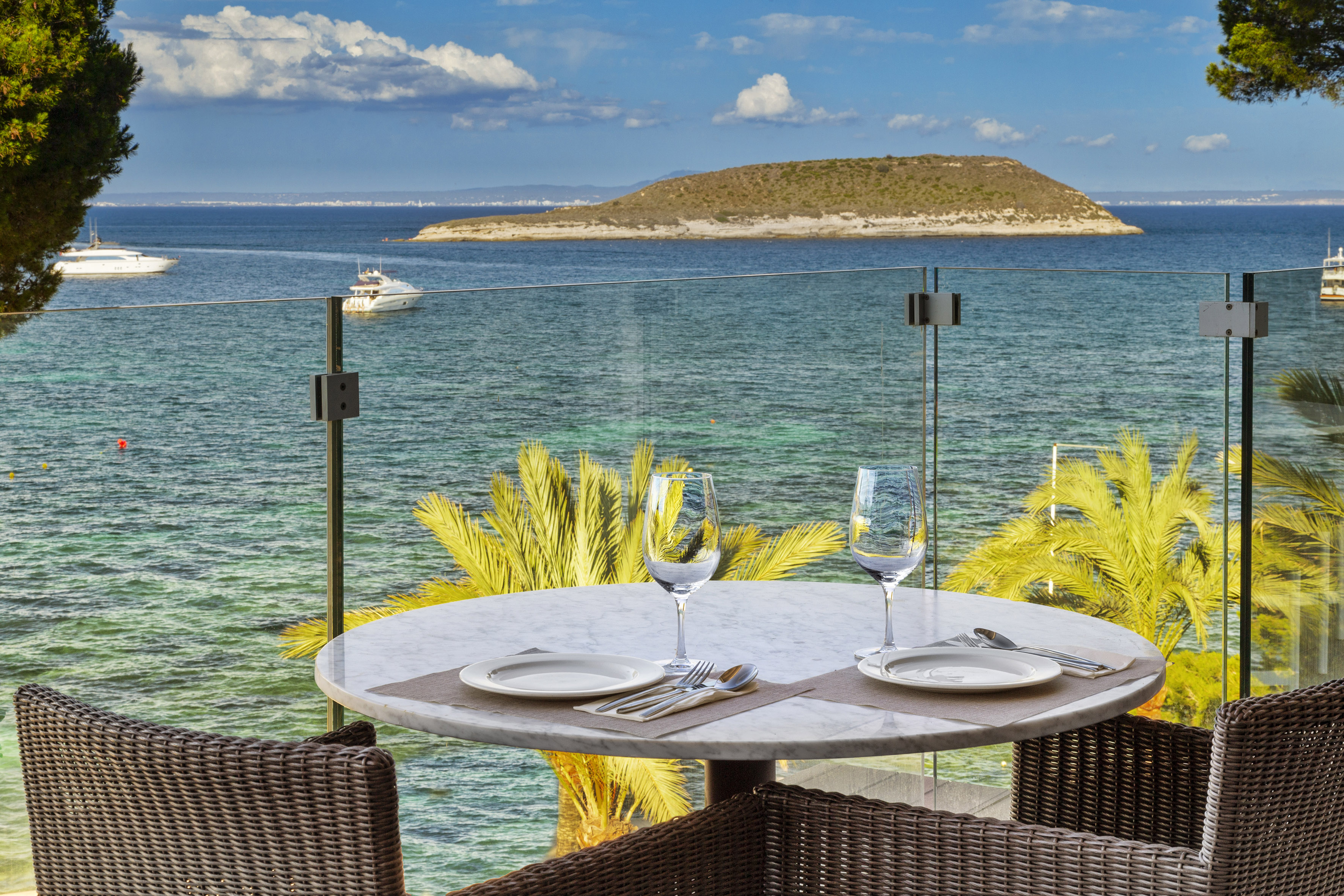Balcony dining table with sea view, distant island, and yachts.
