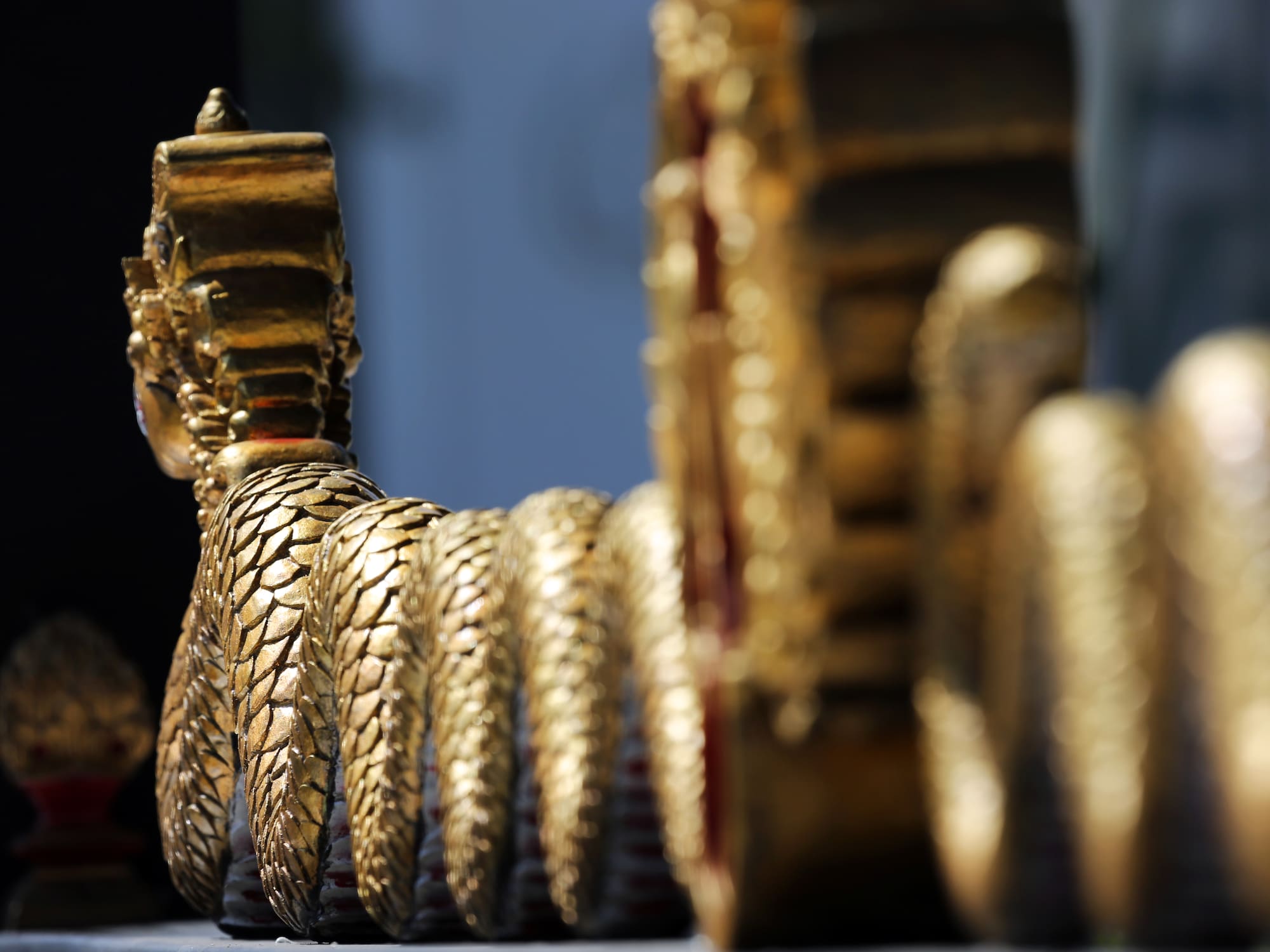 Golden scaled Naga sculpture detail, ornate temple decoration.