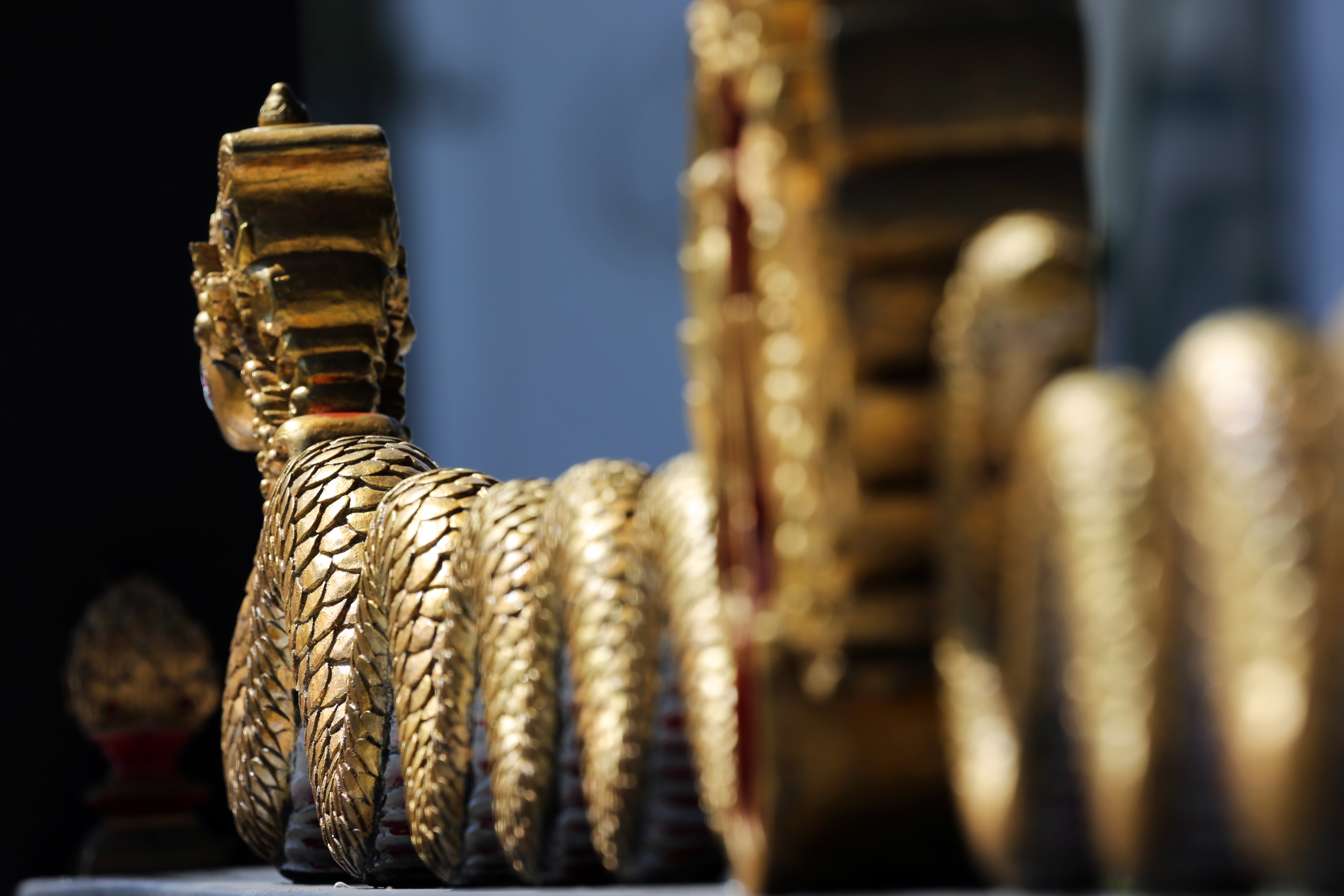 Golden scaled Naga sculpture detail, ornate temple decoration.