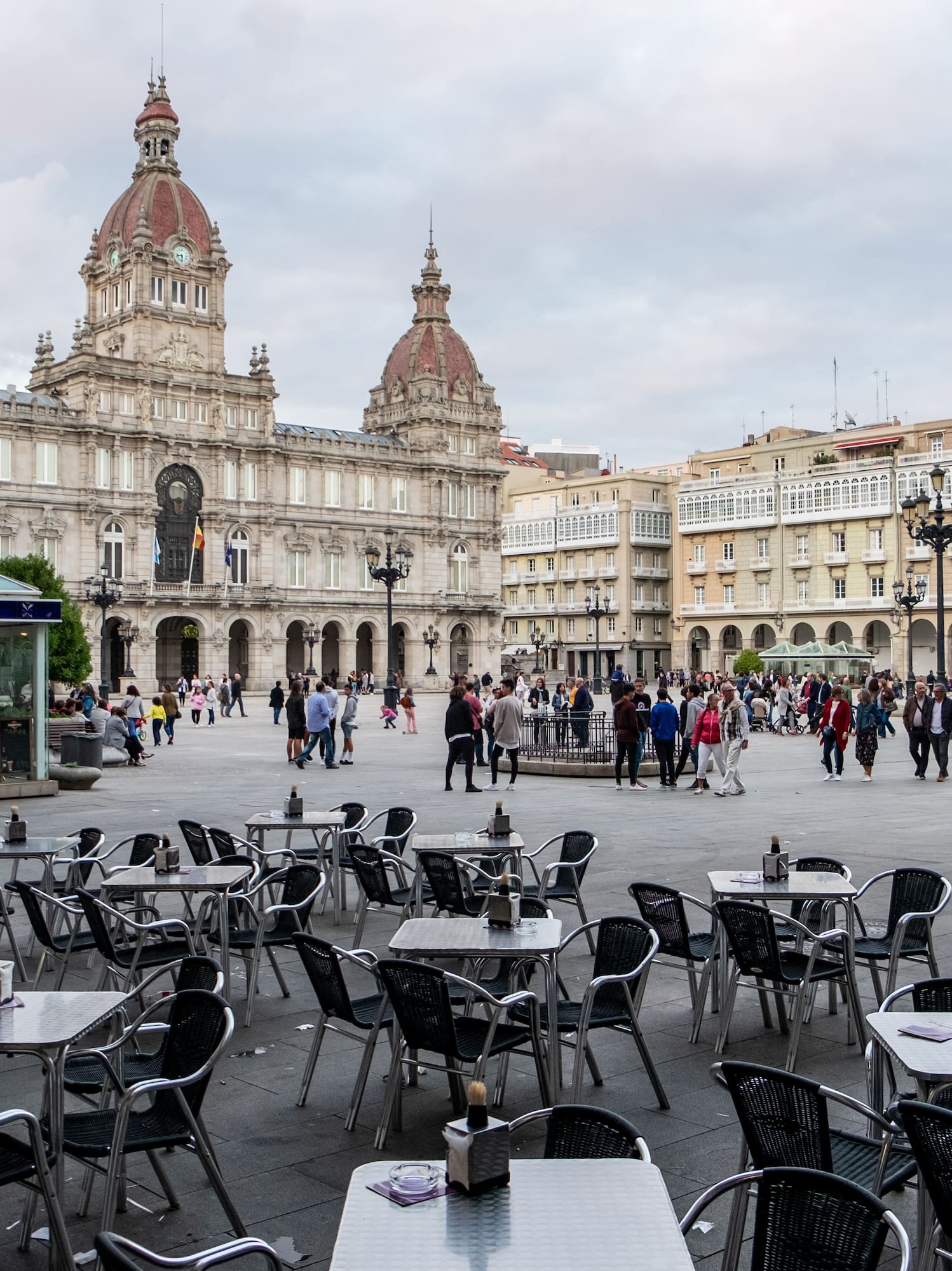 a group of people walking around tables and chairs in a plaza
