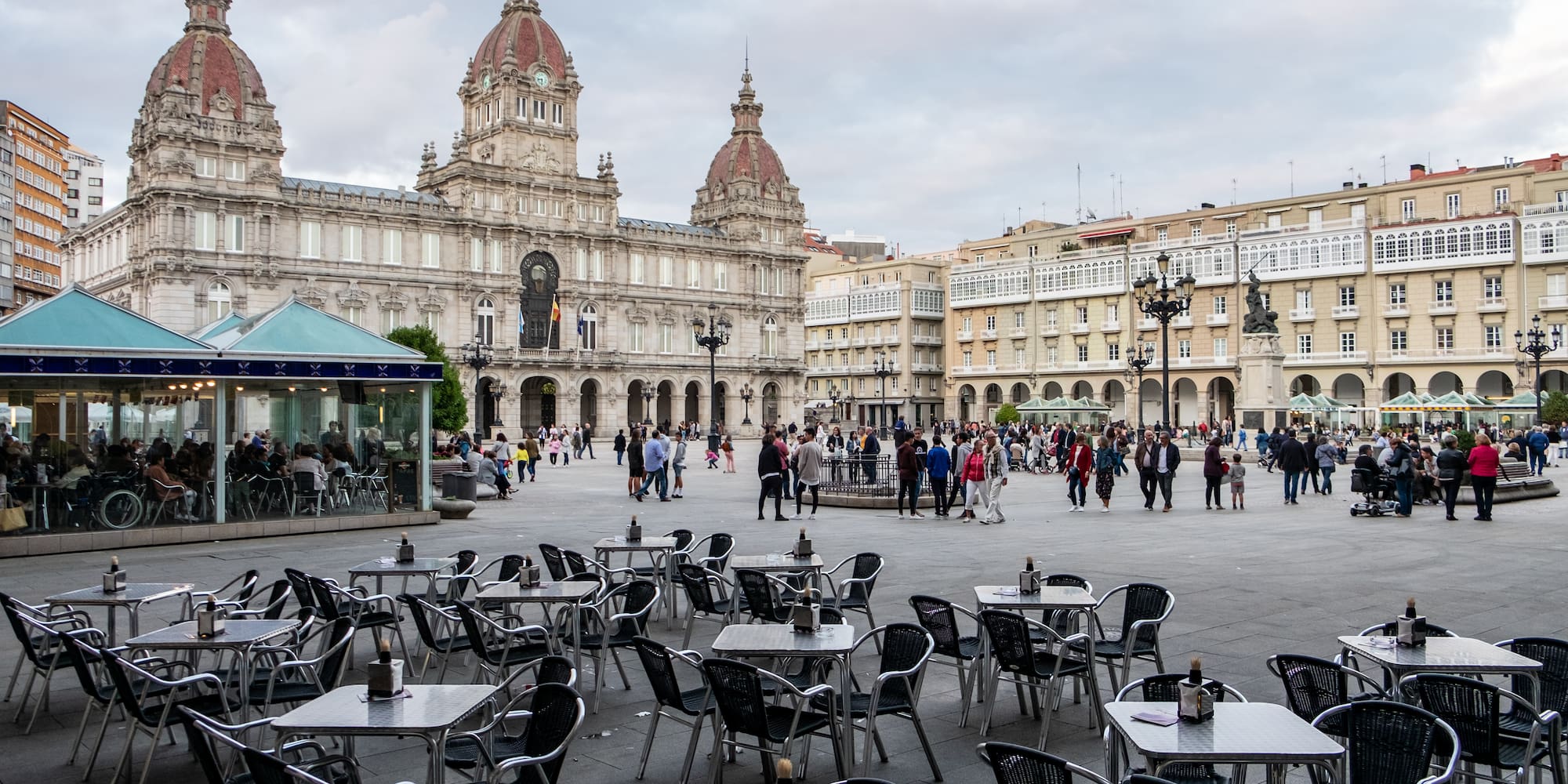 a group of people walking around tables and chairs in a plaza