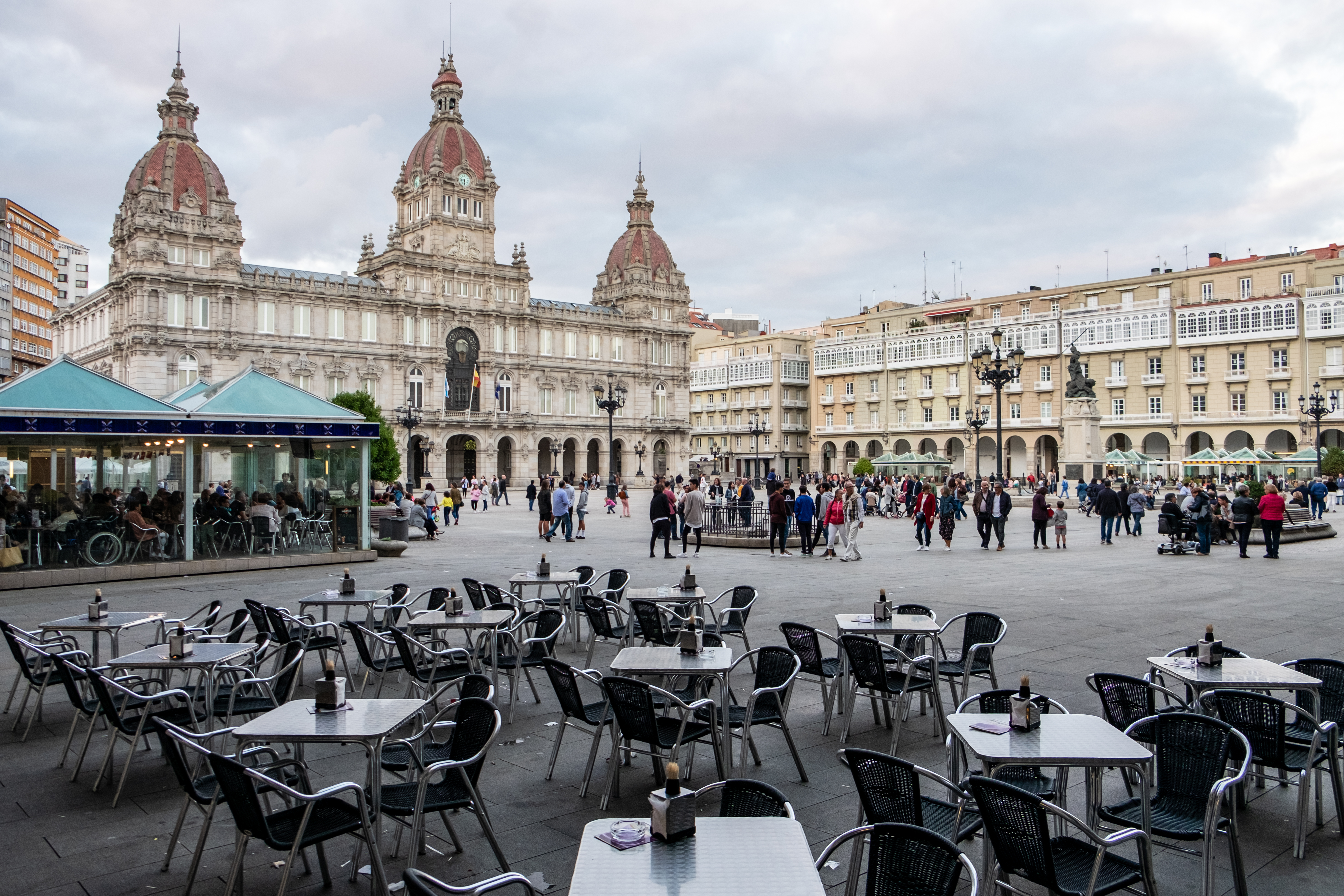 a group of people walking around tables and chairs in a plaza