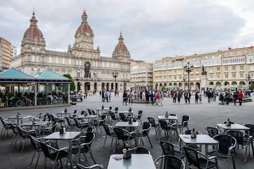 a group of people walking around tables and chairs in a plaza