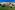 Sunny Mediterranean resort hotel, green garden, olive trees, and tiled dome.