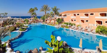 a swimming pool with palm trees and a building